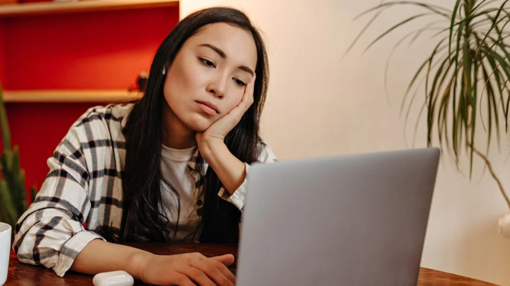 Woman looking bored viewing a laptop screen