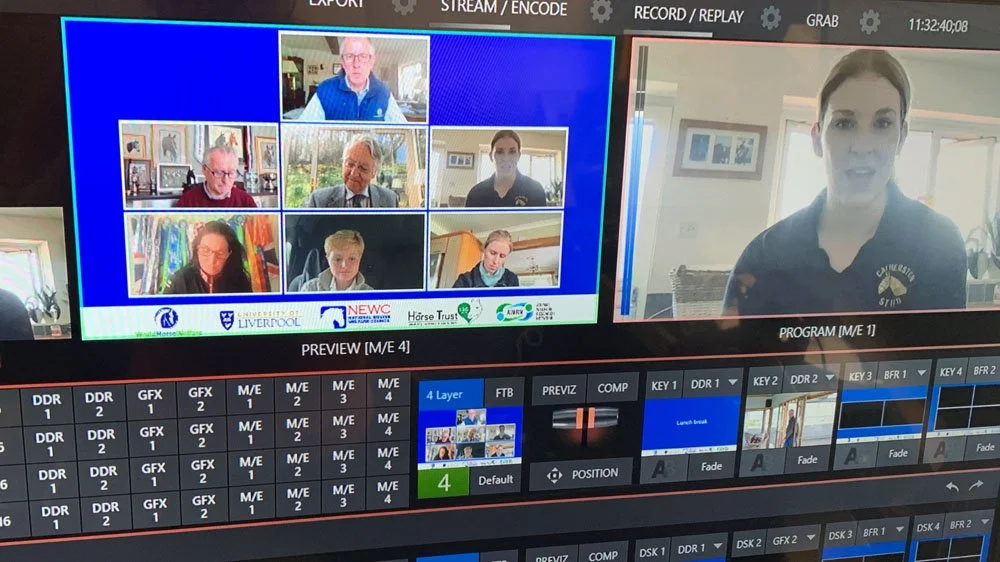 Video production monitor showing a virtual meeting with eight participants in video call and a presenter on the right. The screen also displays timeline and editing controls at the bottom.