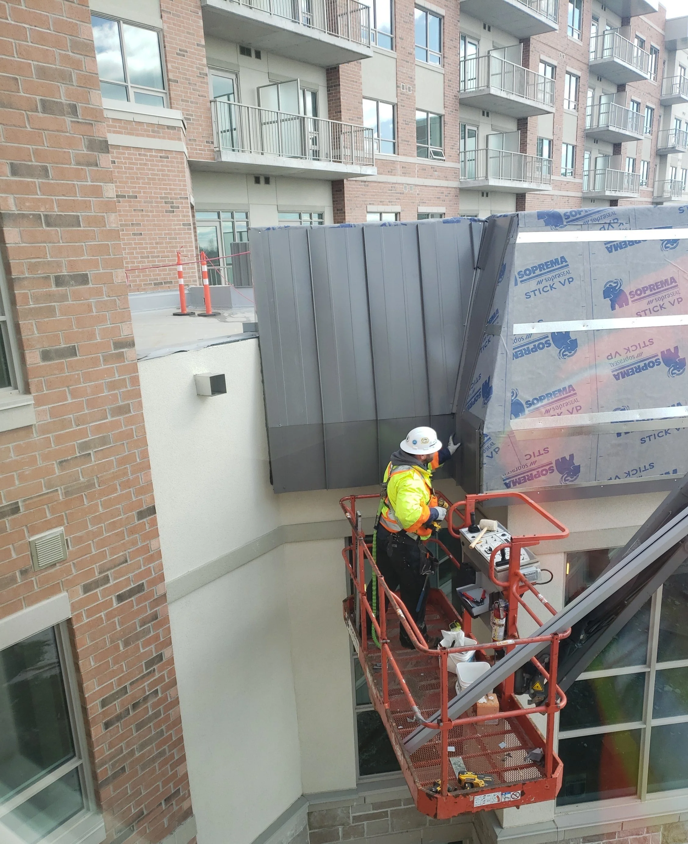 Construction workers on a scaffold working on a building exterior, installing or repairing metal panels and insulation.