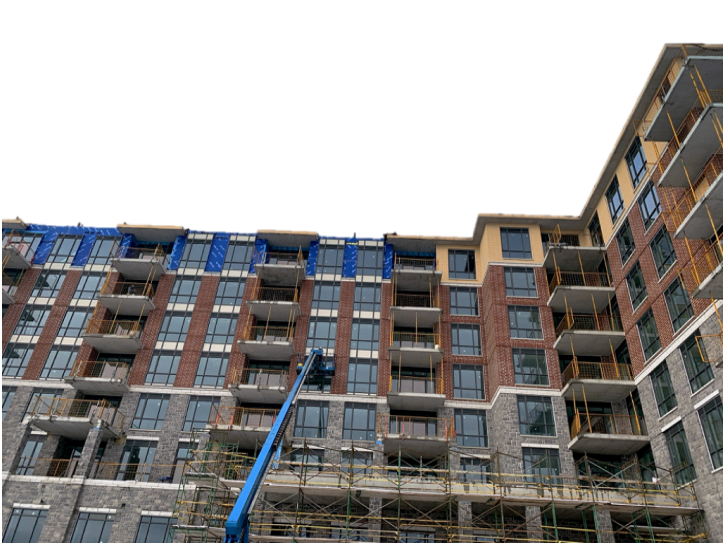 A multi-story residential building under construction with scaffolding and a crane, featuring brick and glass exterior walls.