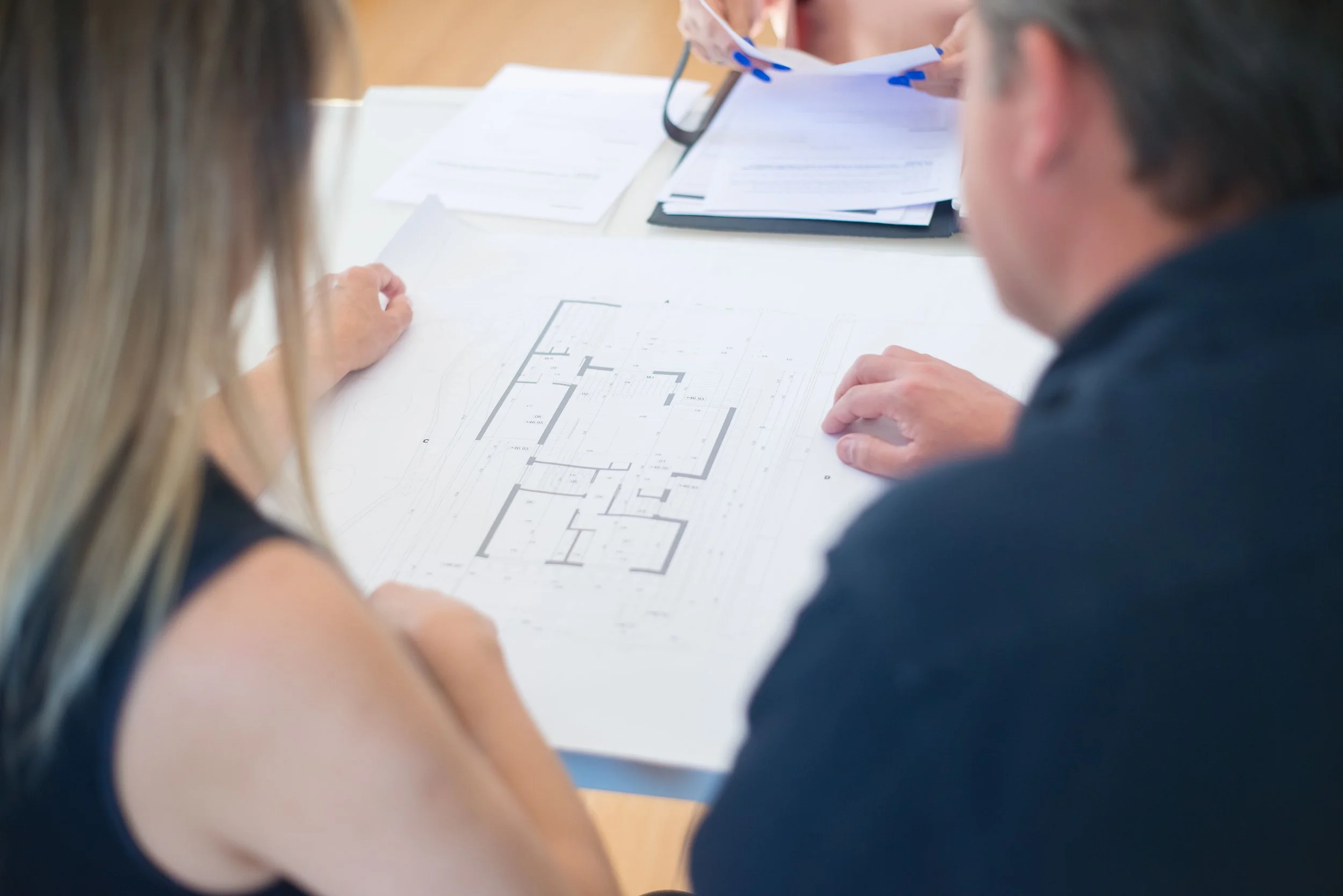 People reviewing architectural blueprints and documents at a table.