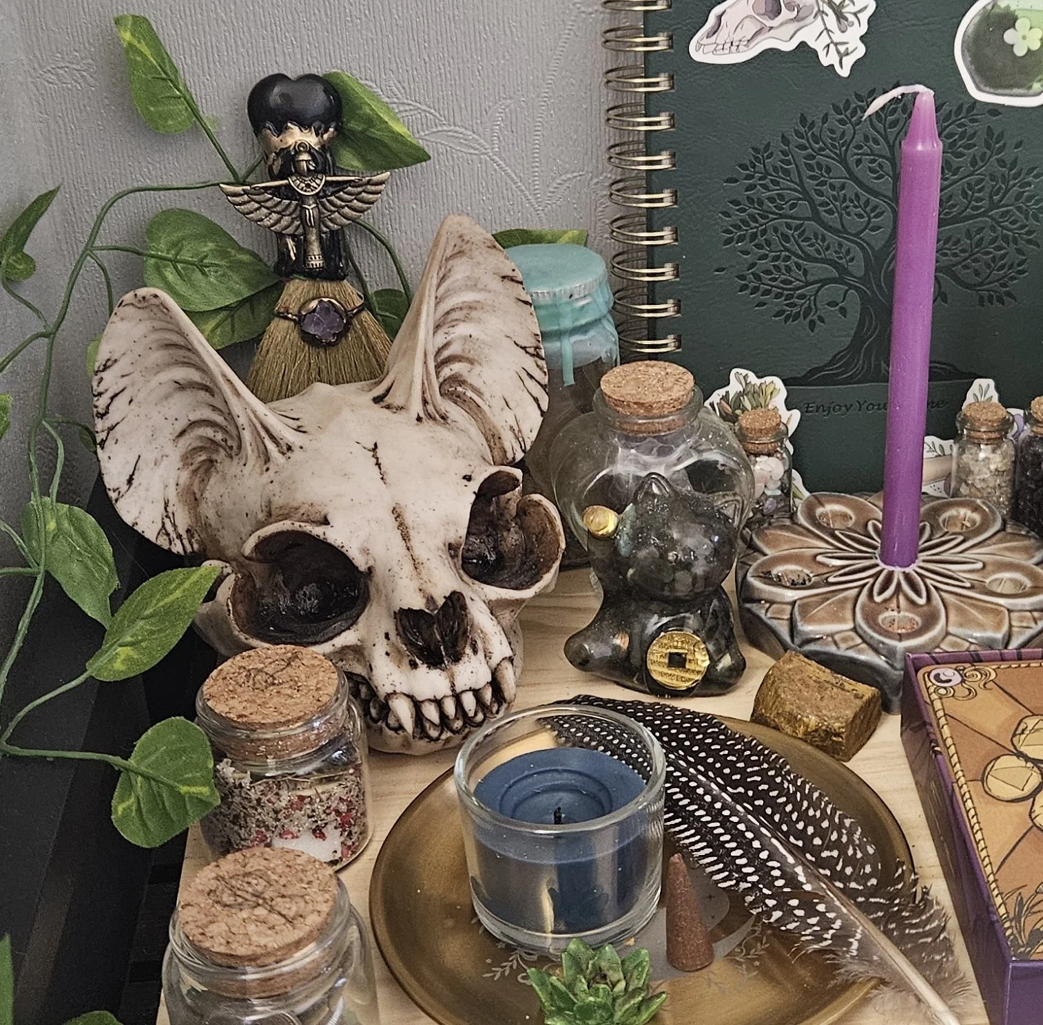 A miniature white magick witch altar featuring a detailed replica cat skull, burning ritual candles, and sacred geometry tools for spirit servitor energy work.