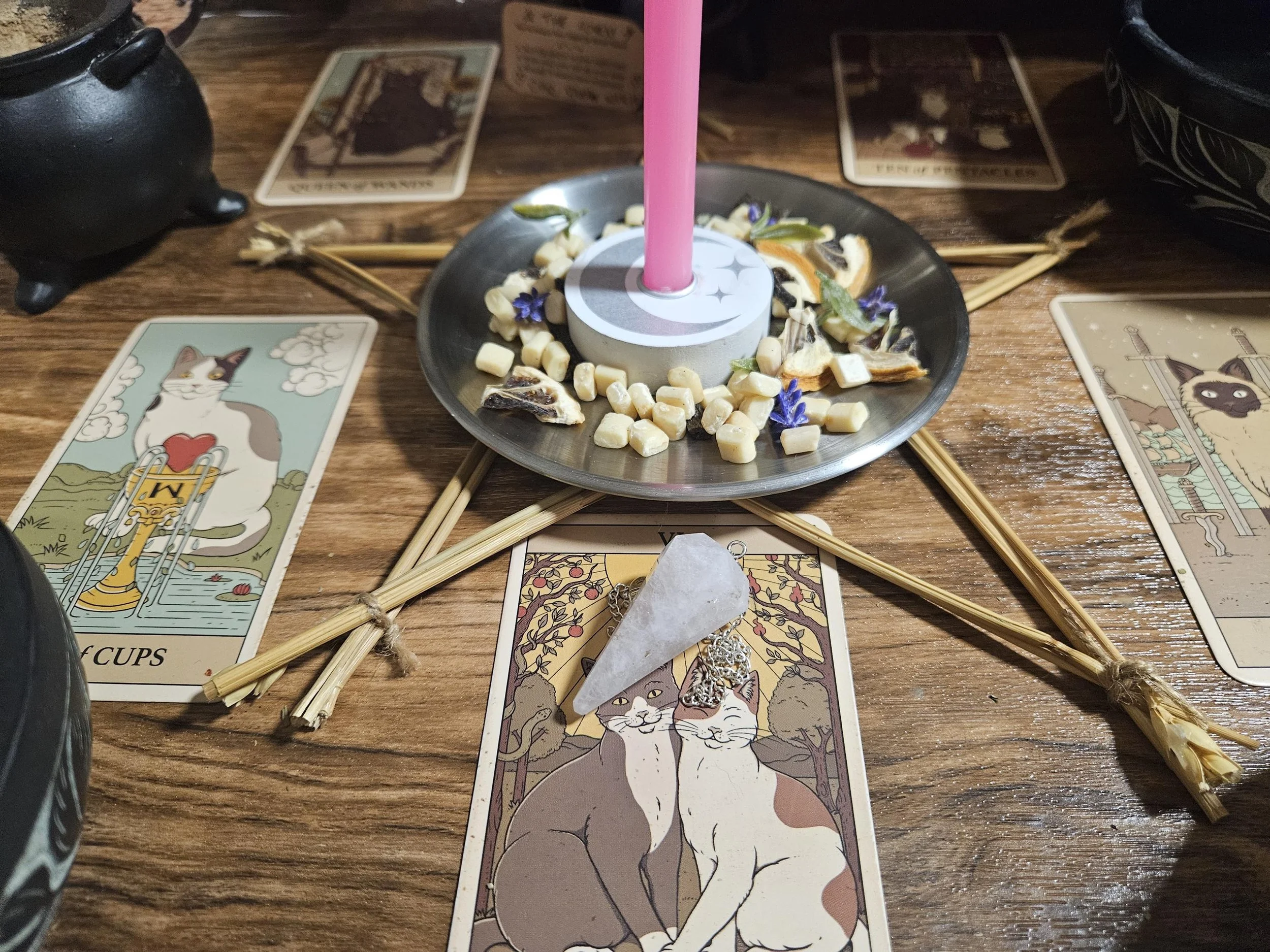 Rose Quartz gemstone pendant talisman on an altar with pink candles and dried petals.