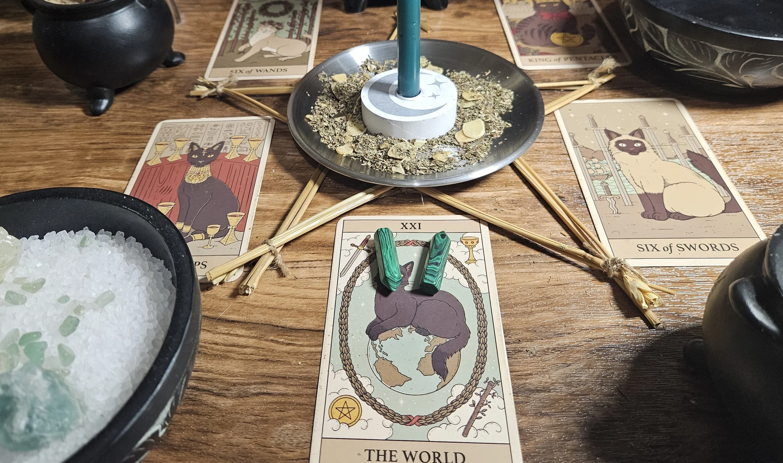 A tabletop featuring a glowing candle, an array of tarot cards, and a wooden spoon resting beside them.