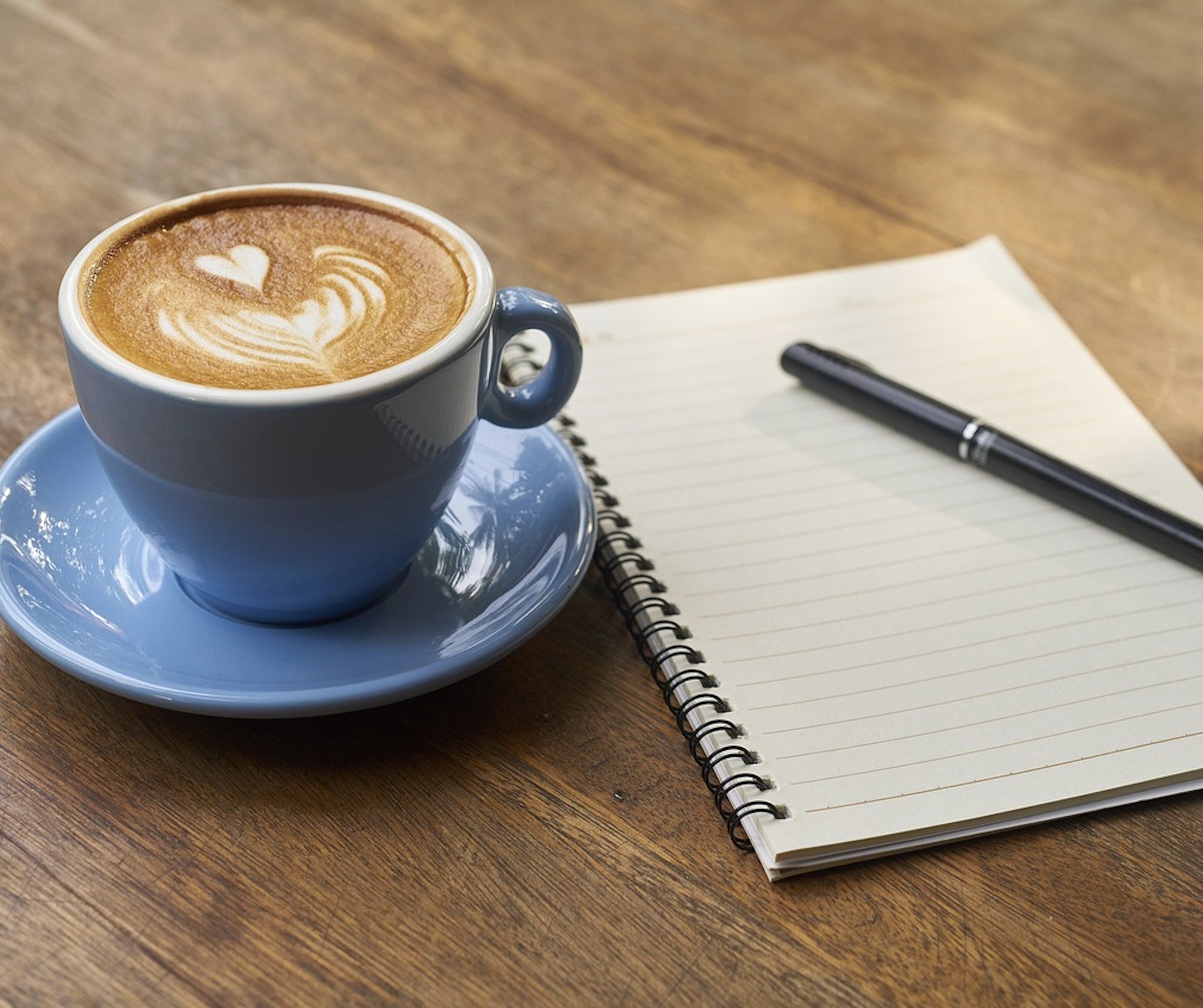 A cozy, top-down shot of a warm ceramic mug sitting on a wooden nightstand next to a raw amethyst crystal and a simple notebook.
