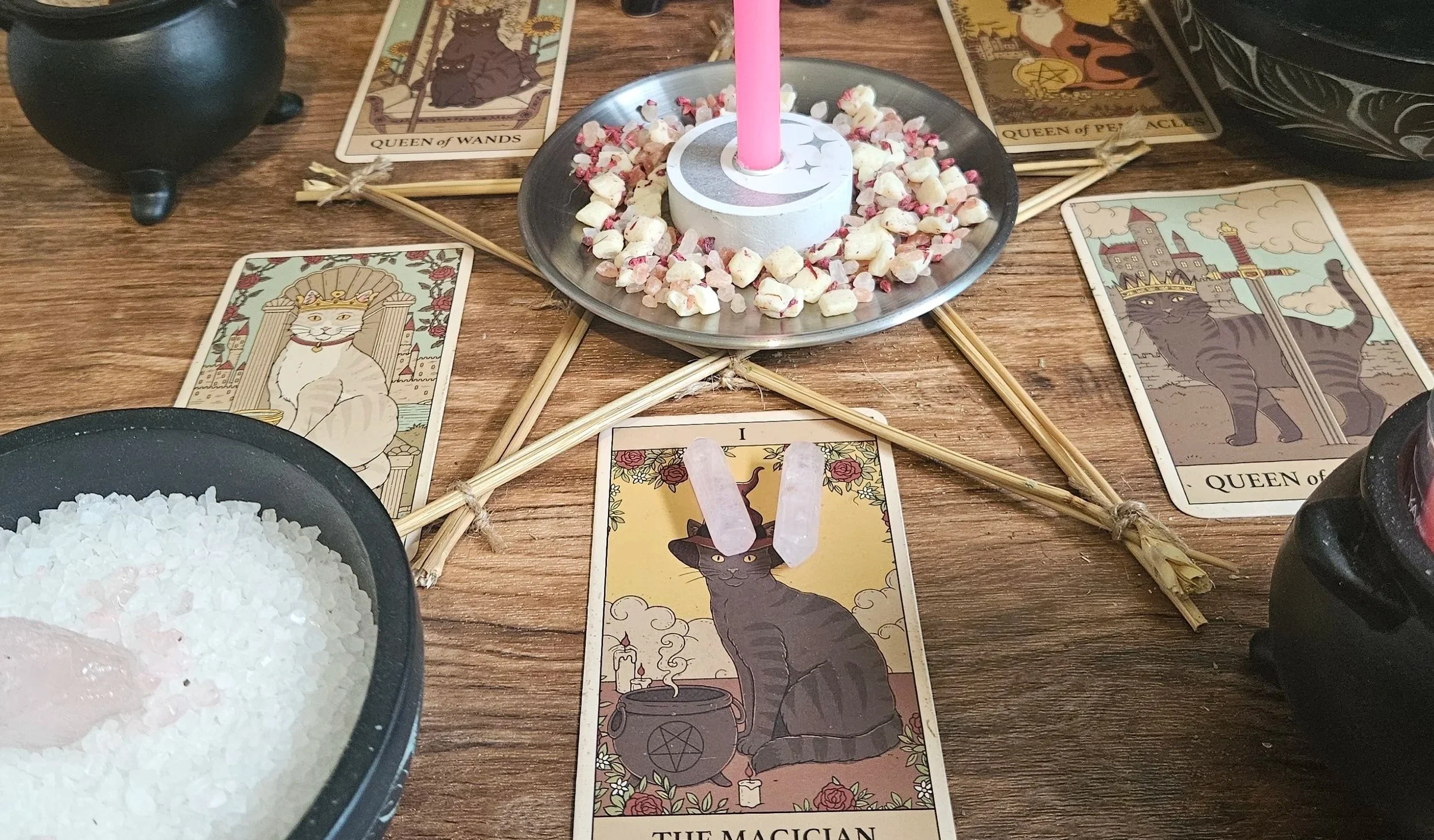A table displaying tarot cards, lit candles, and various mystical items arranged for a reading session.