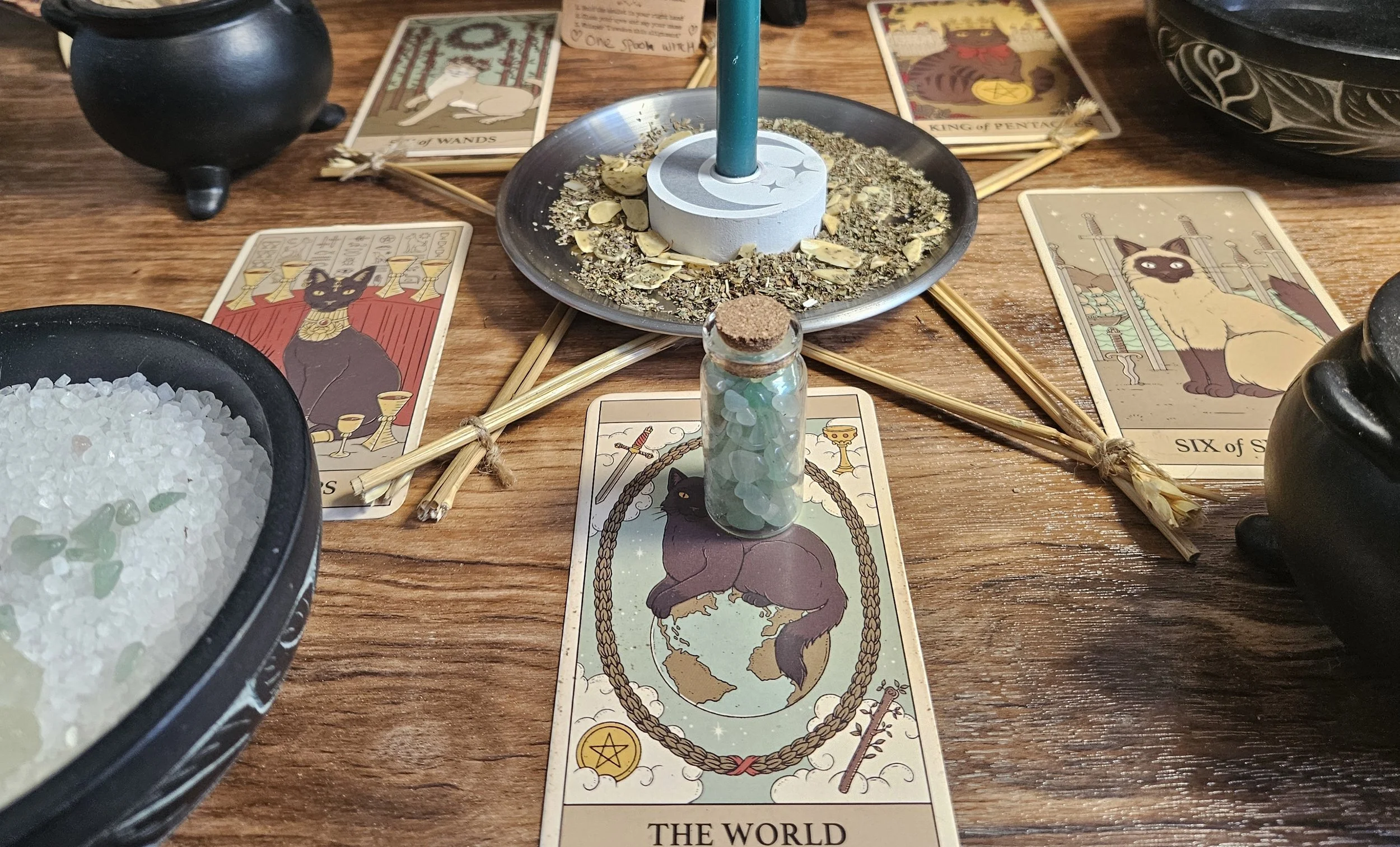 A candle, a tarot card, and a bowl of herbs arranged together, suggesting a spiritual or ritualistic setting.