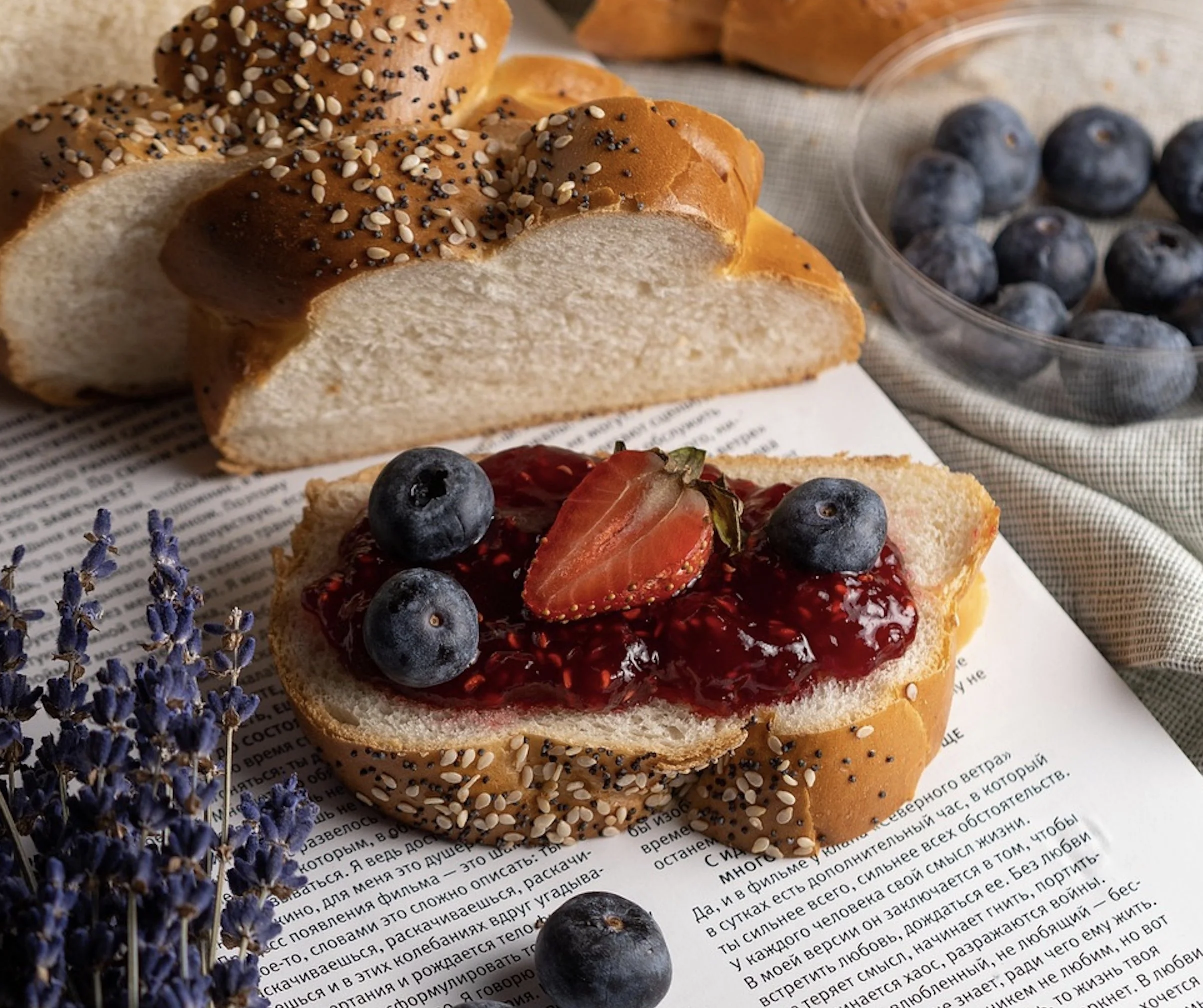 A beautifully warm flatlay of a golden baked loaf of bread resting on a rustic cloth next to wheat stalks and burning orange candles.