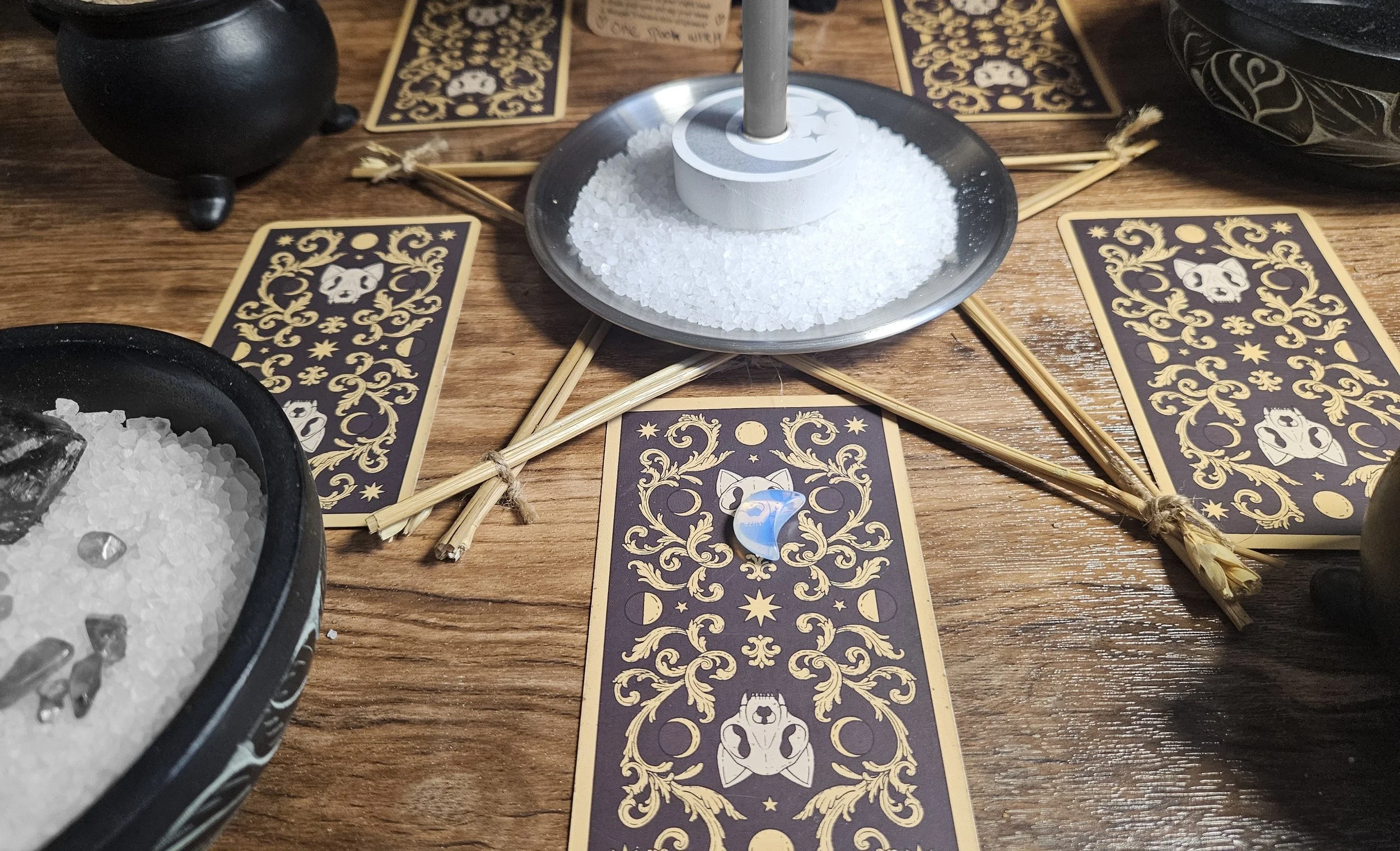 A close-up photograph showcasing the optional tiny moon-shaped rainbow moonstone crystal amulet upgrade included with the custom spell package.