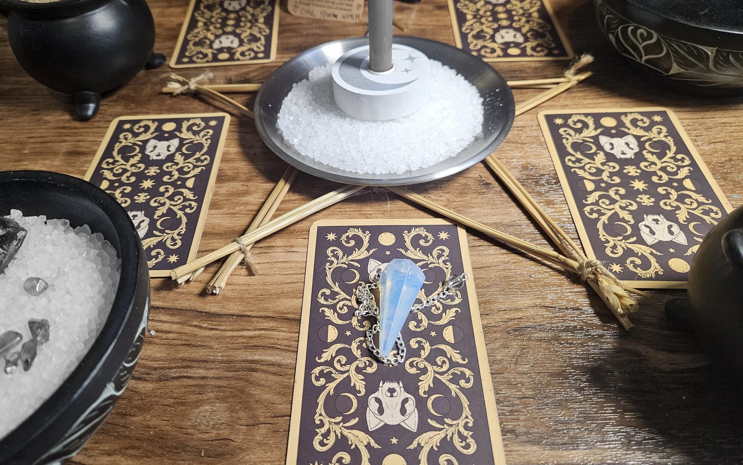 A close-up product photograph of a polished rainbow moonstone crystal pendulum used for divination and energy work.