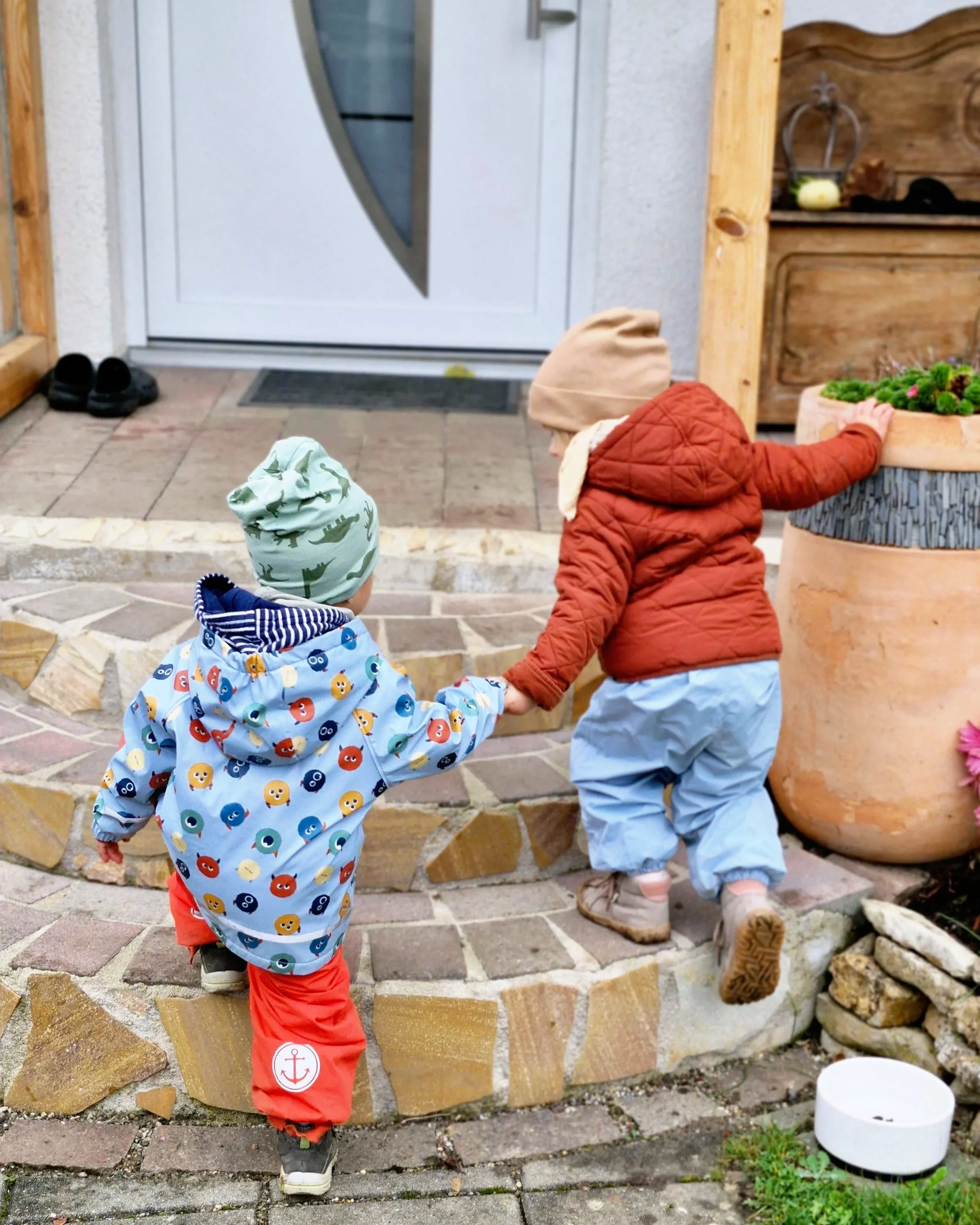 Ein Mädchen zieht einen Jungen an der Hand die Treppe zur Haustüre des Kuhbergnests hinauf.