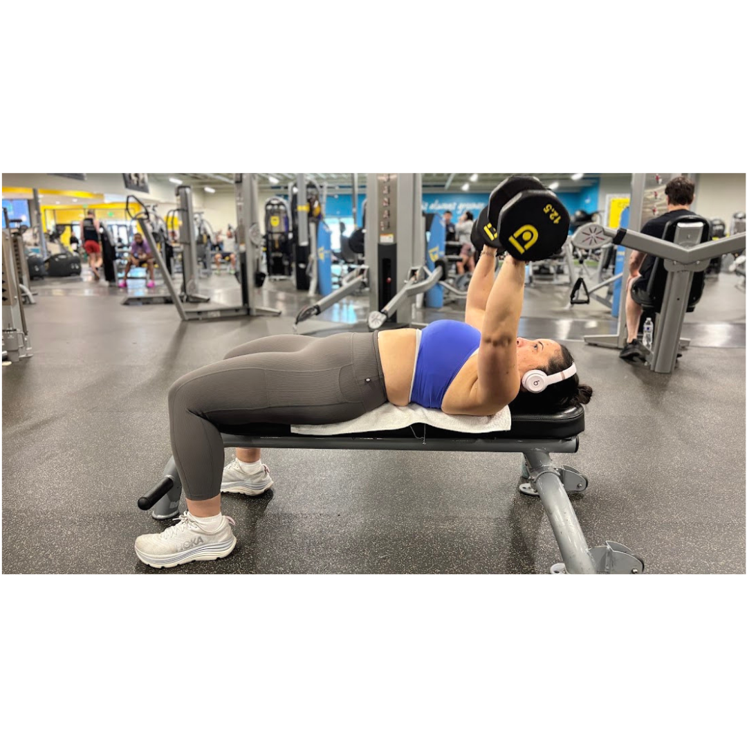 Woman performing a dumbbell bench press as part of a resistance training routine for heart health