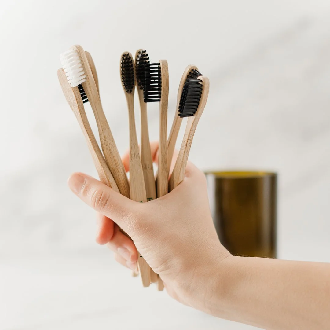 Image of someone holding a handful of wooden toothbrushes. 
