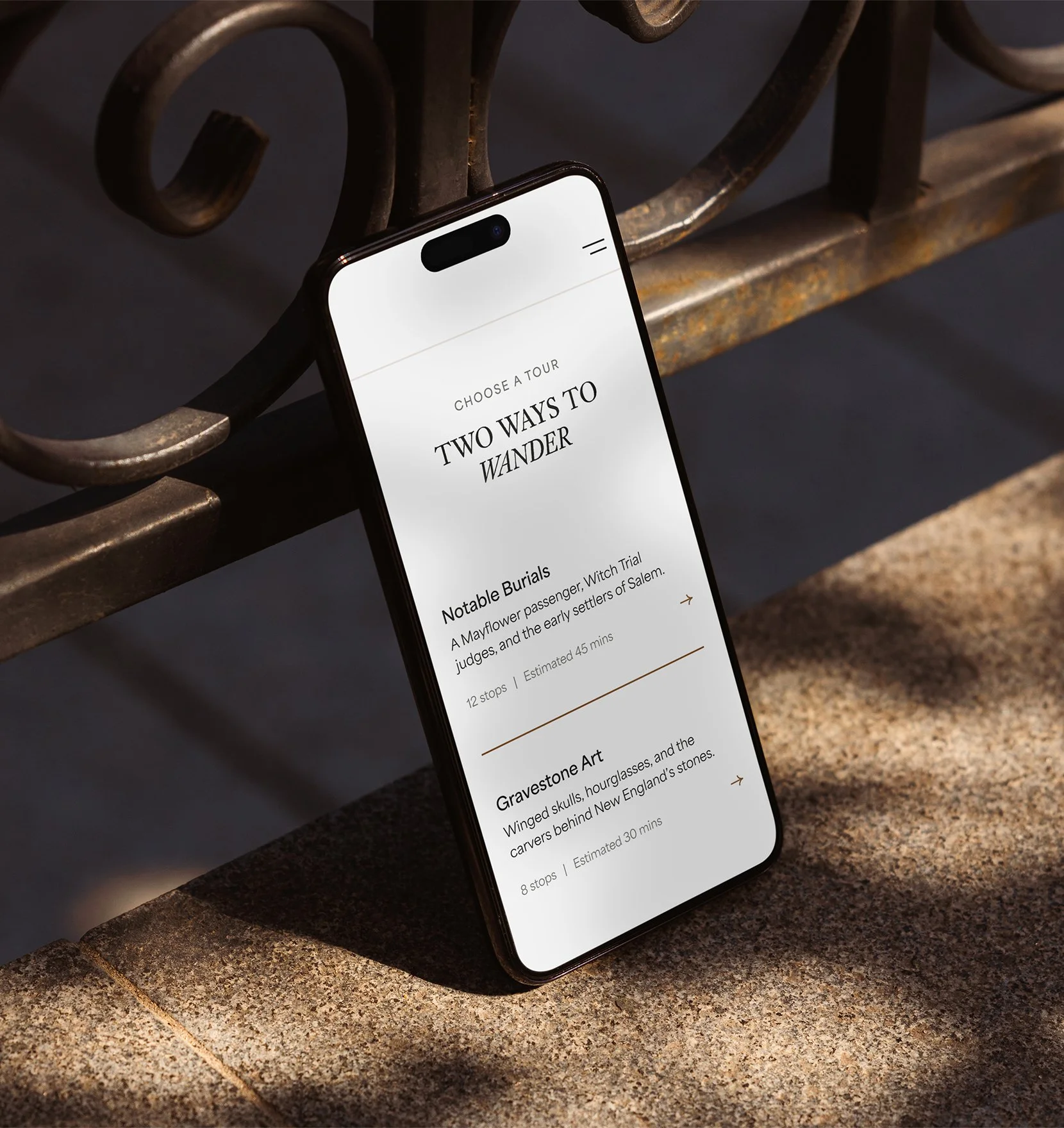 Phone prompted up on stone wall, showing the start screen for a self-guided tour.