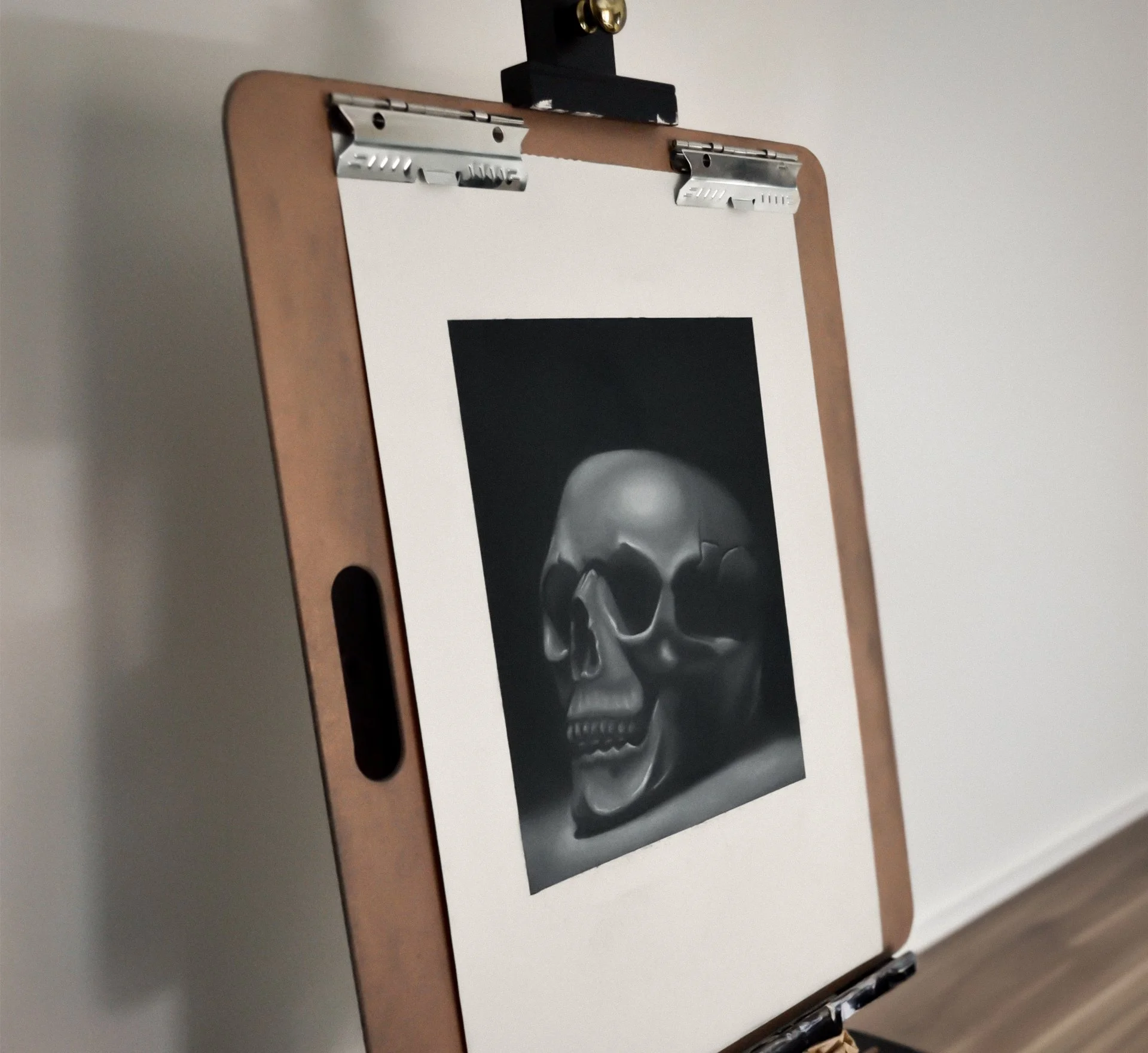 Easel holding a charcoal drawing of a human skull.