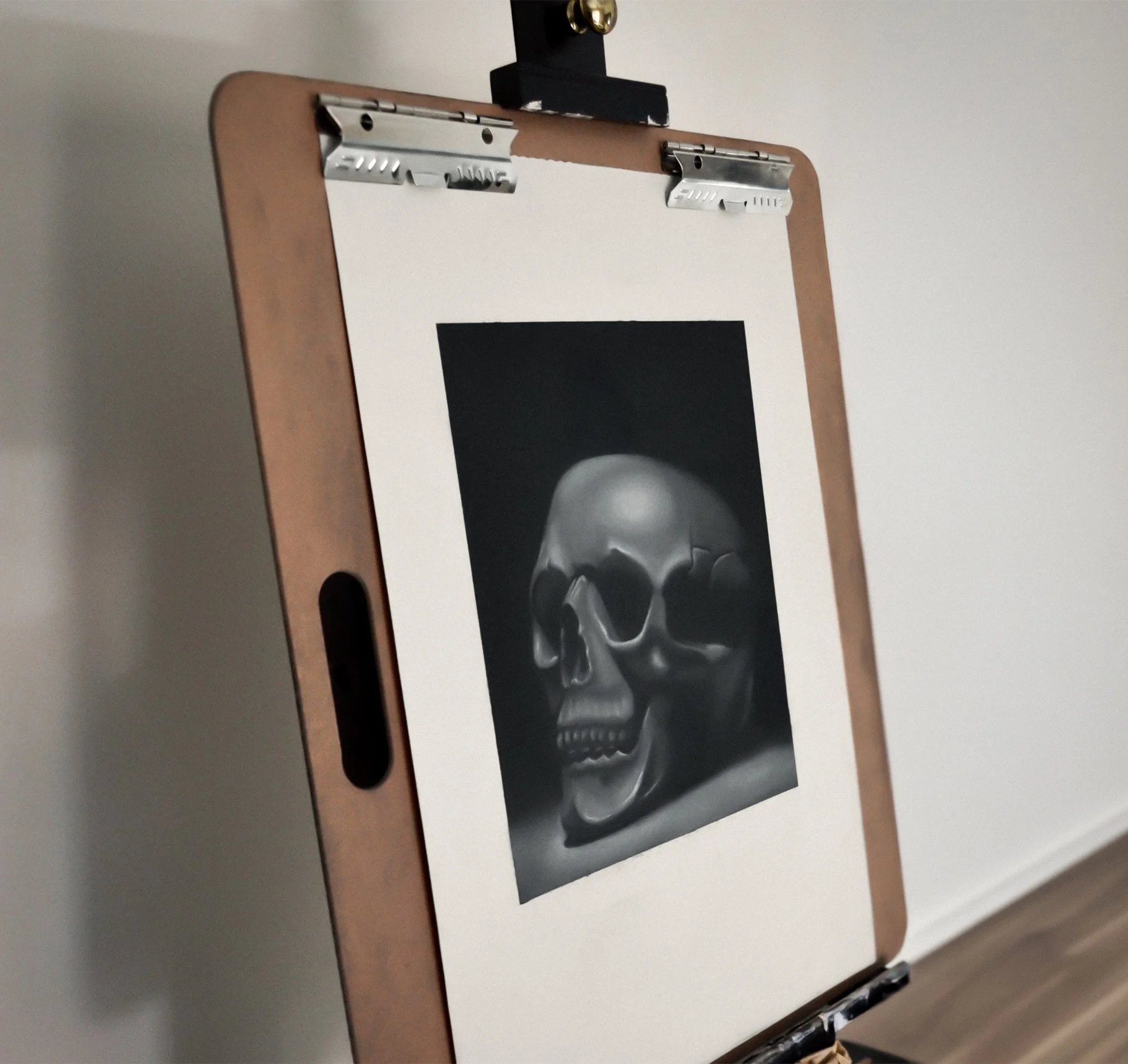 Easel holding a charcoal drawing of a human skull.