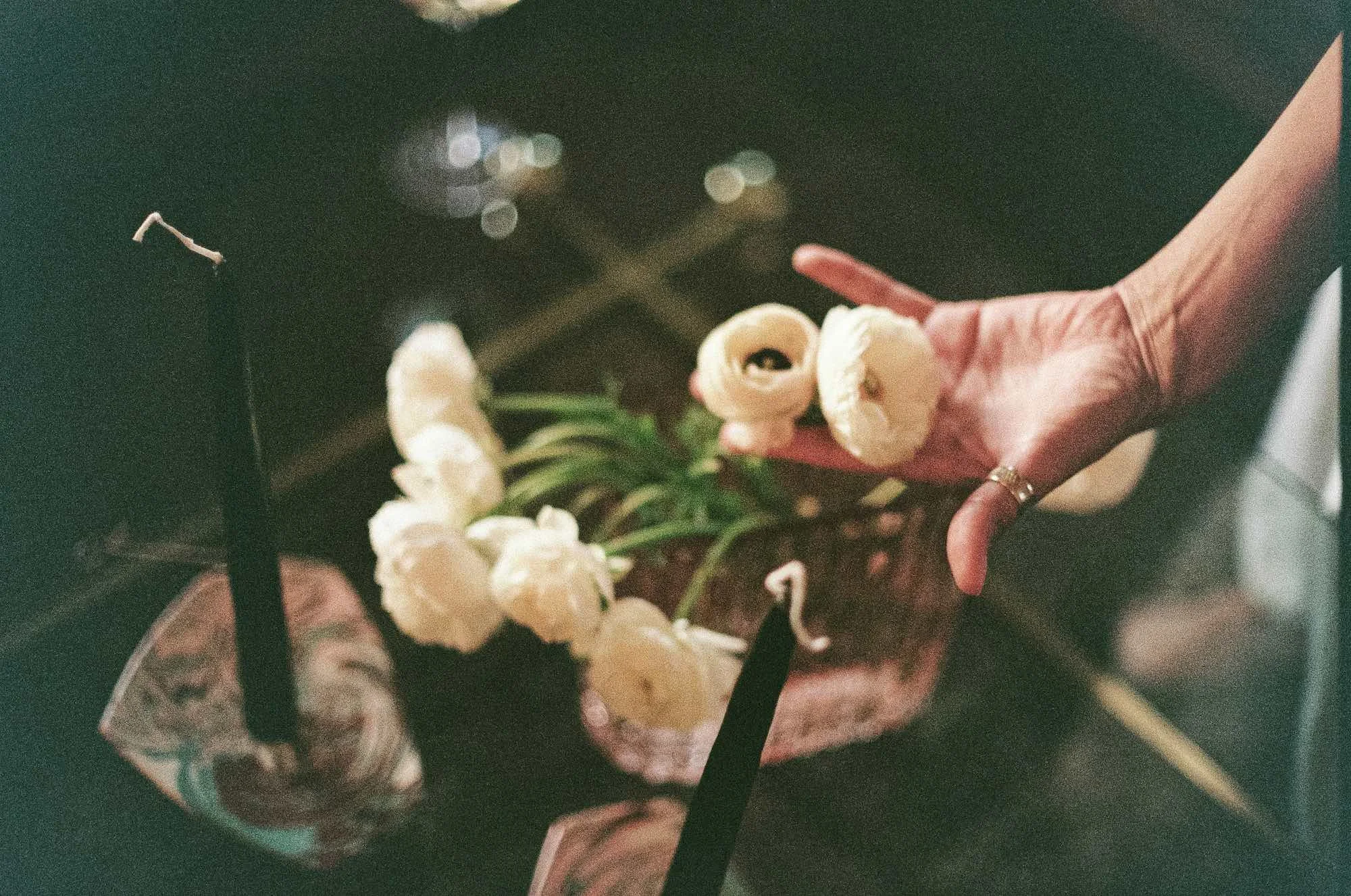 A person in a pink jacket holding a small bouquet of light-colored flowers