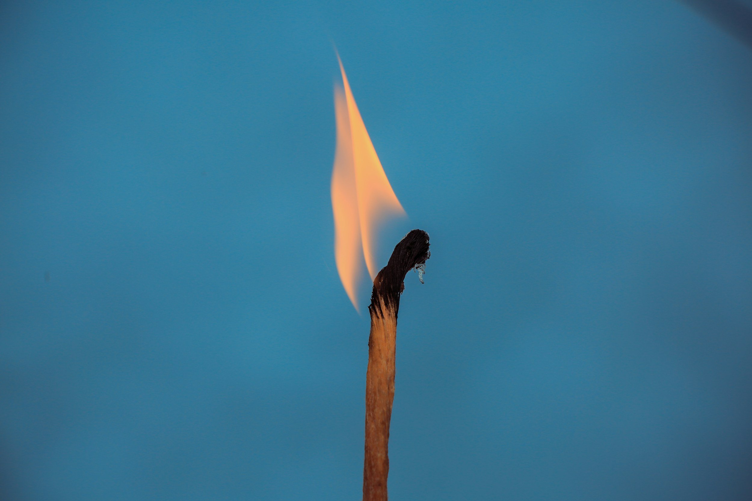 A matchstick with a flame against a blue background.