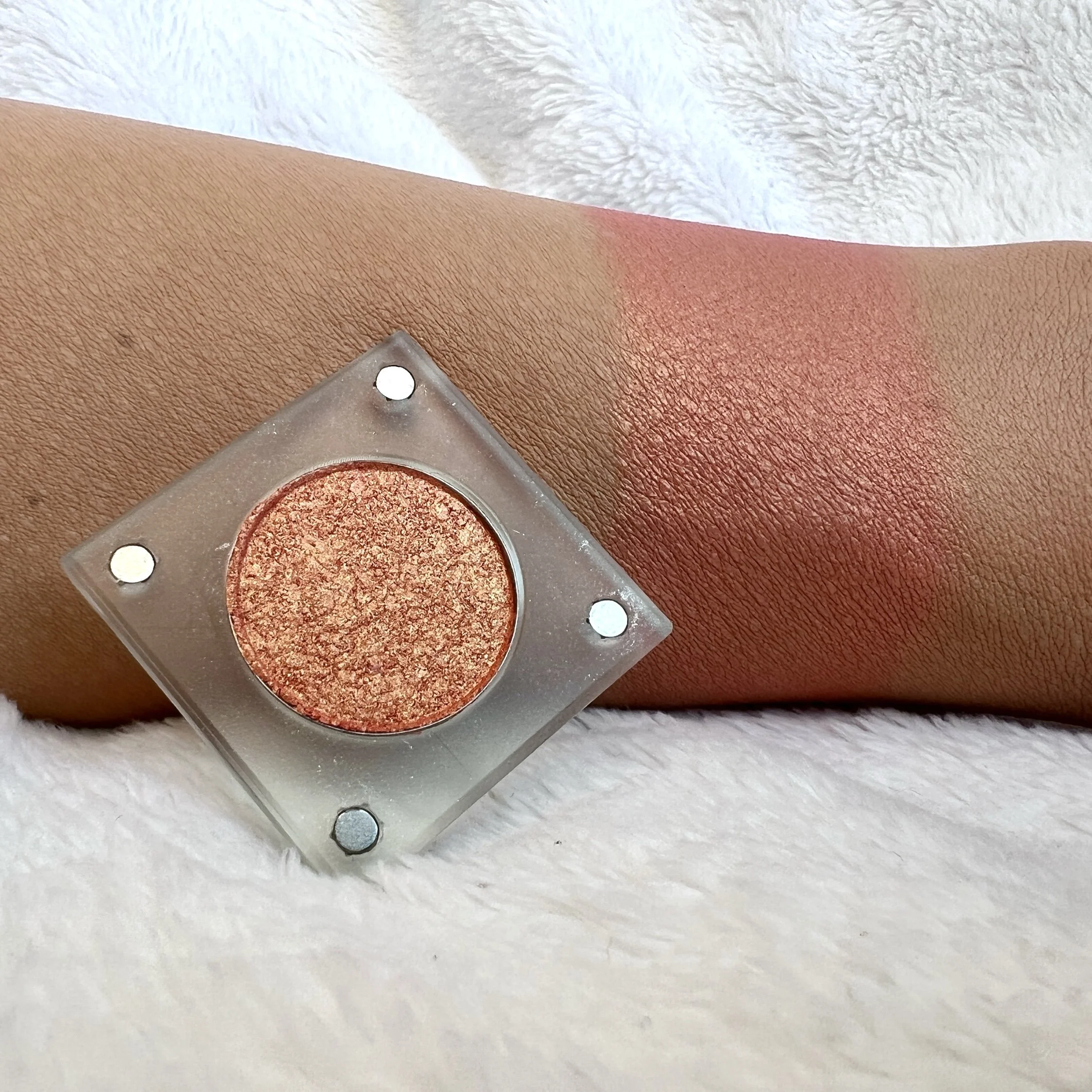 Hands to Crown by The Imperfectionist: warm copper-rose shimmer eyeshadow swatched on medium skin next to an open pan.