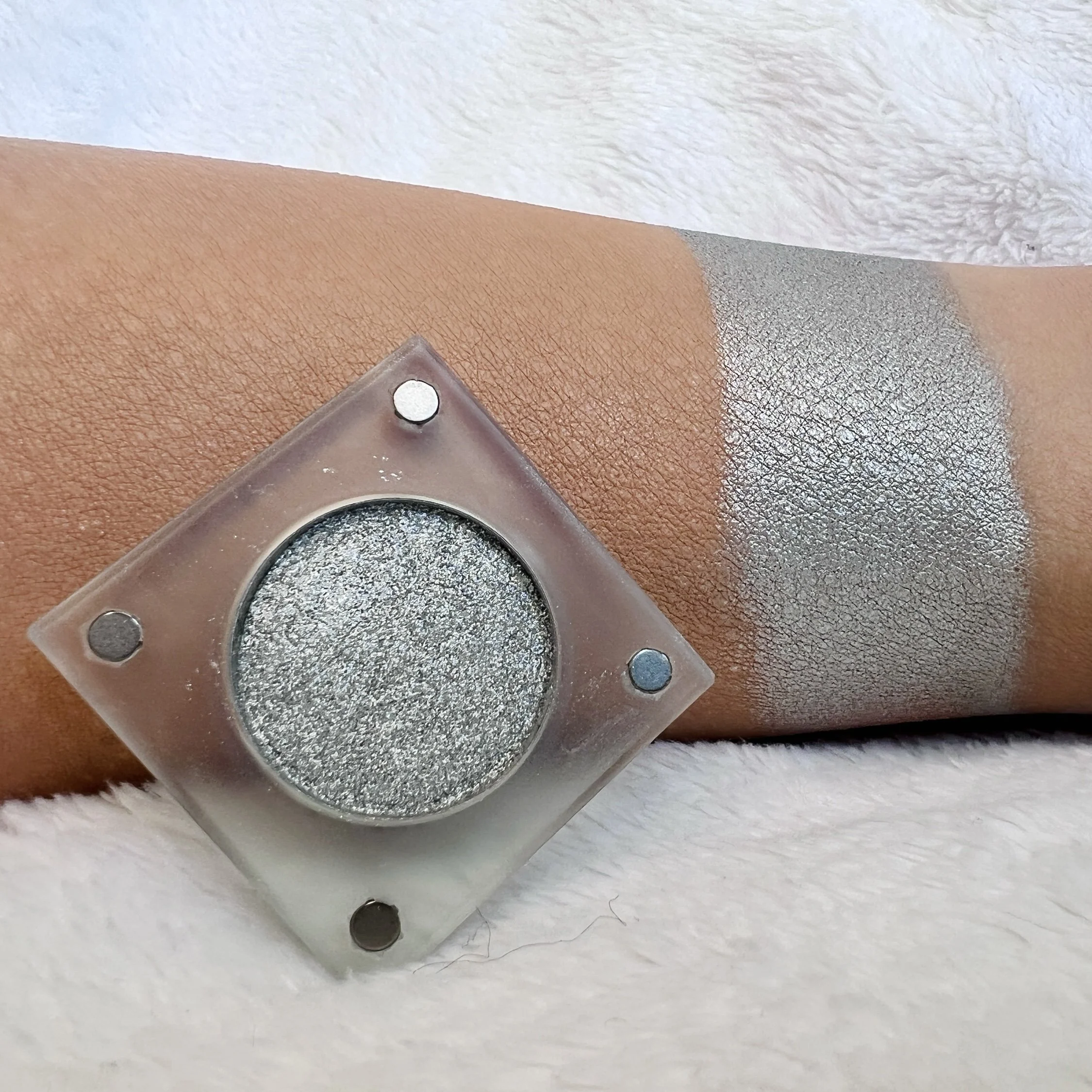 Read My Lips by The Imperfectionist: cool metallic silver eyeshadow swatched on medium skin beside an open shimmer pan.