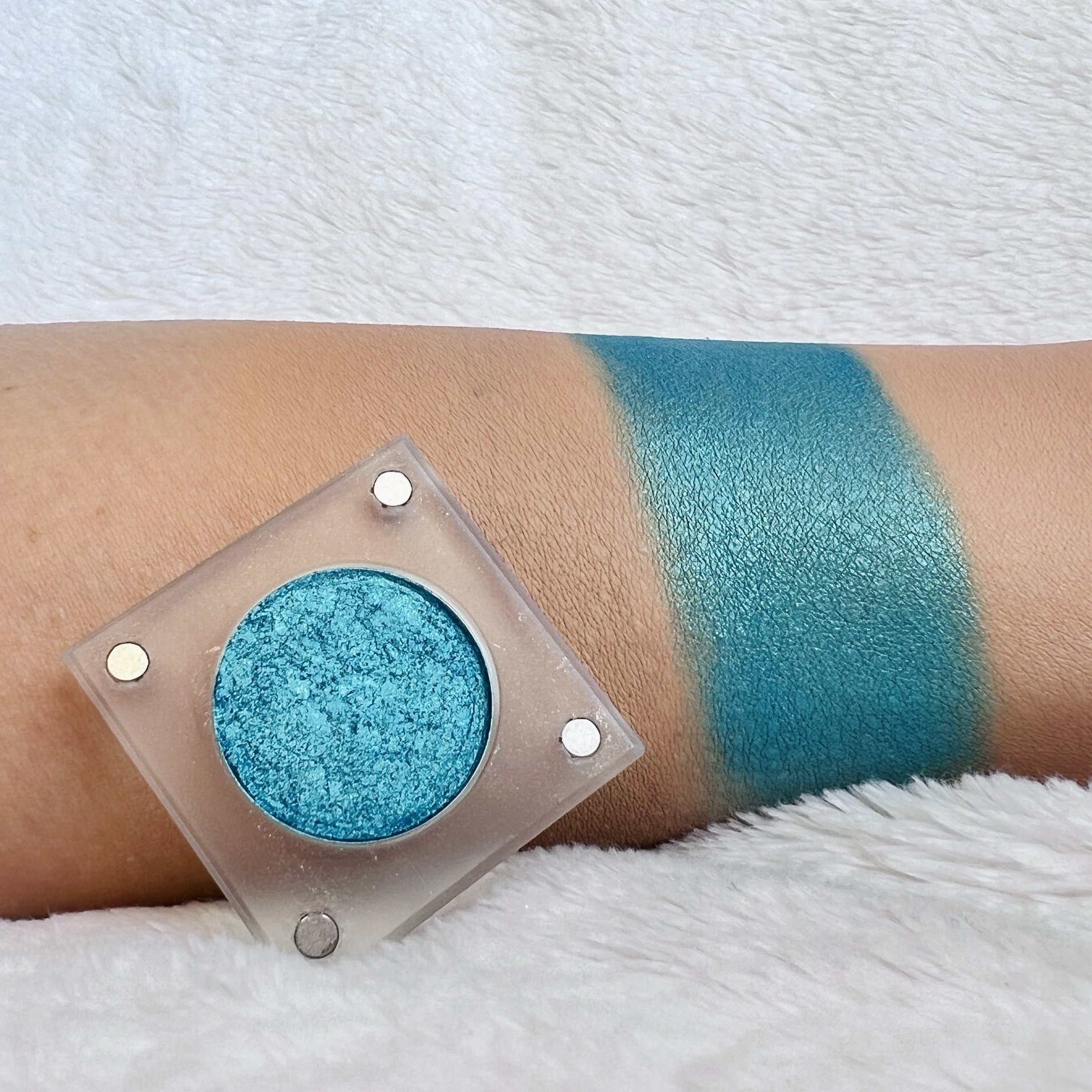 Breathtaking Glow by The Imperfectionist: vivid turquoise-teal shimmer eyeshadow swatched on medium skin beside an open pan.