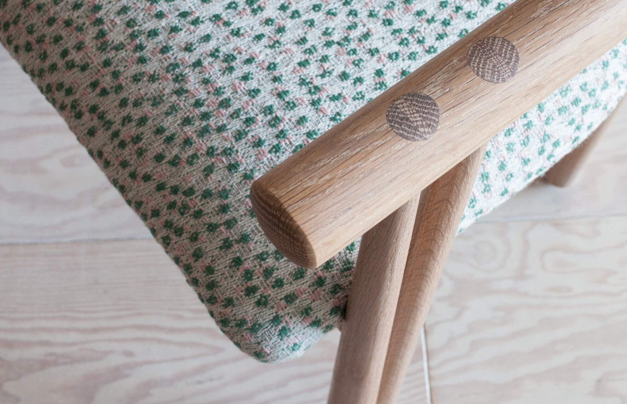 Detail of a wood chair arm with green and pink polka dot fabric design by De La Espada