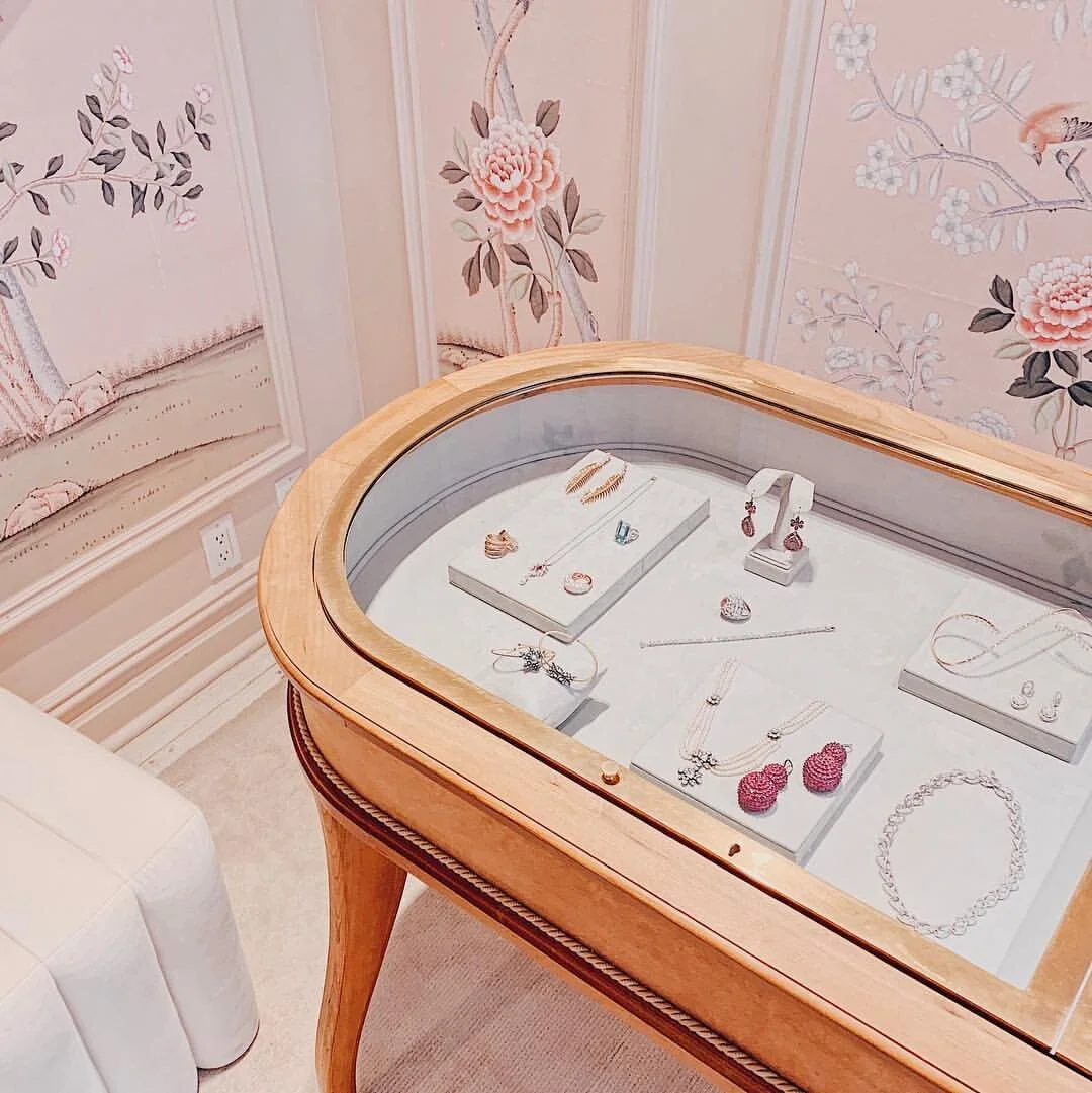 Traditional style wood jewelry display with pink floral wall paper at Moda Operandi in New York City