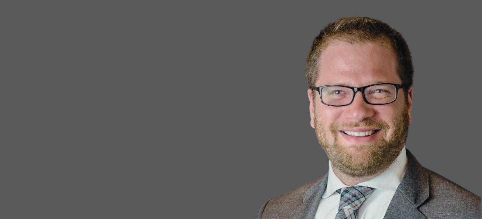 Dr. Seth Blacksburg, Radiation Oncologist, wearing a suit and tie and smiling in front of a gray background.