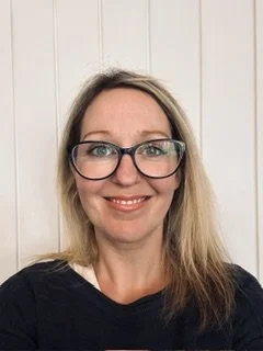 Close-up of a smiling woman wearing large black-rimmed glasses