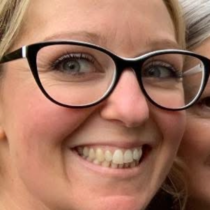 Close-up of a smiling woman wearing large black-rimmed glasses