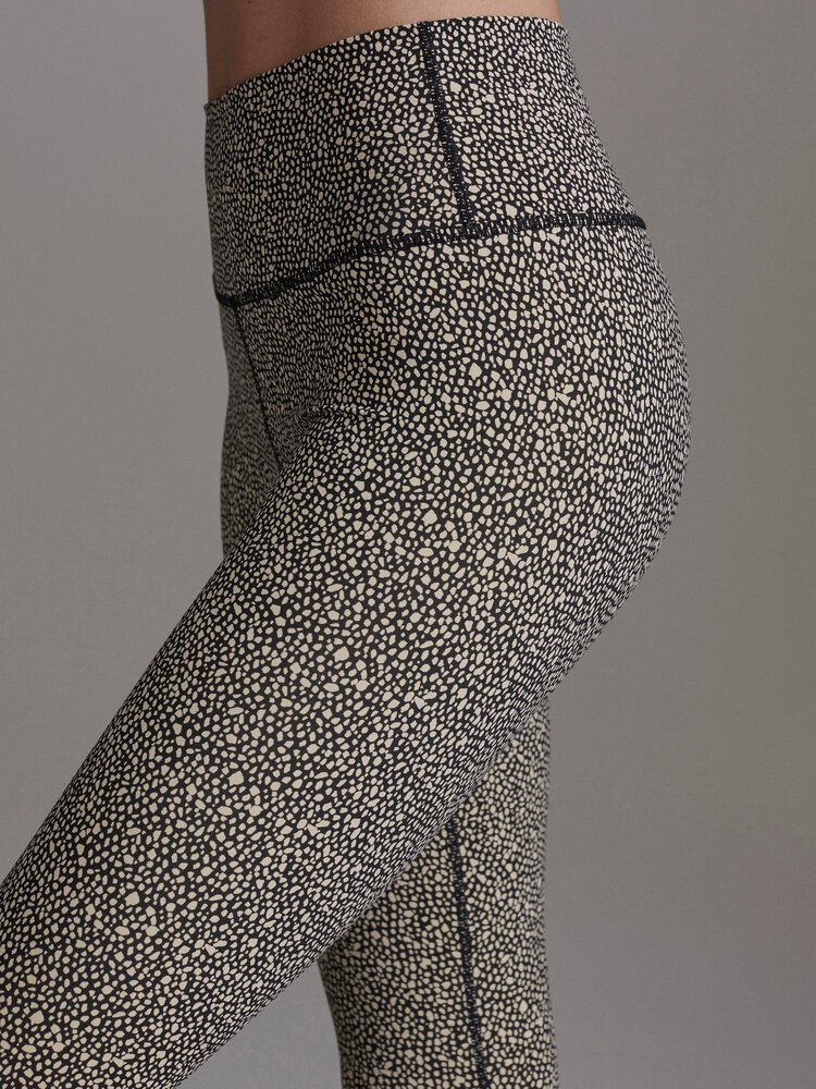 Close-up of a person's lower back and hips wearing high-waisted black and white patterned leggings with a dotted design.