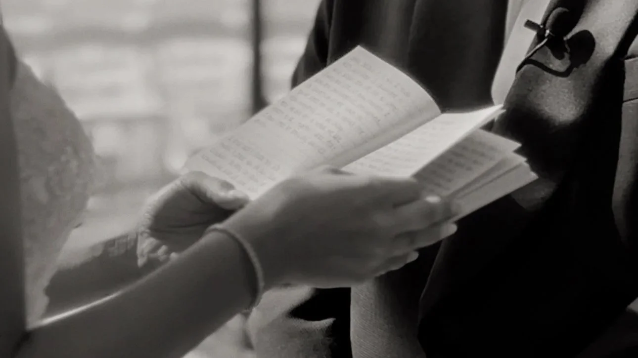 Person reading a book held in their hands in a black and white photo.