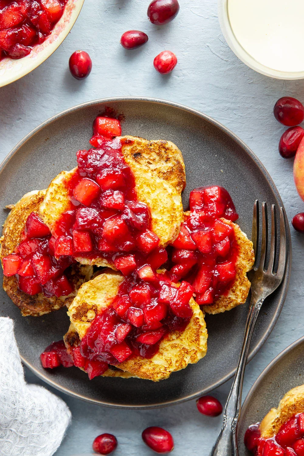A landscape of rolling hills with modern buildings in the foreground and snow-capped mountains in the background under a cloudy sky.