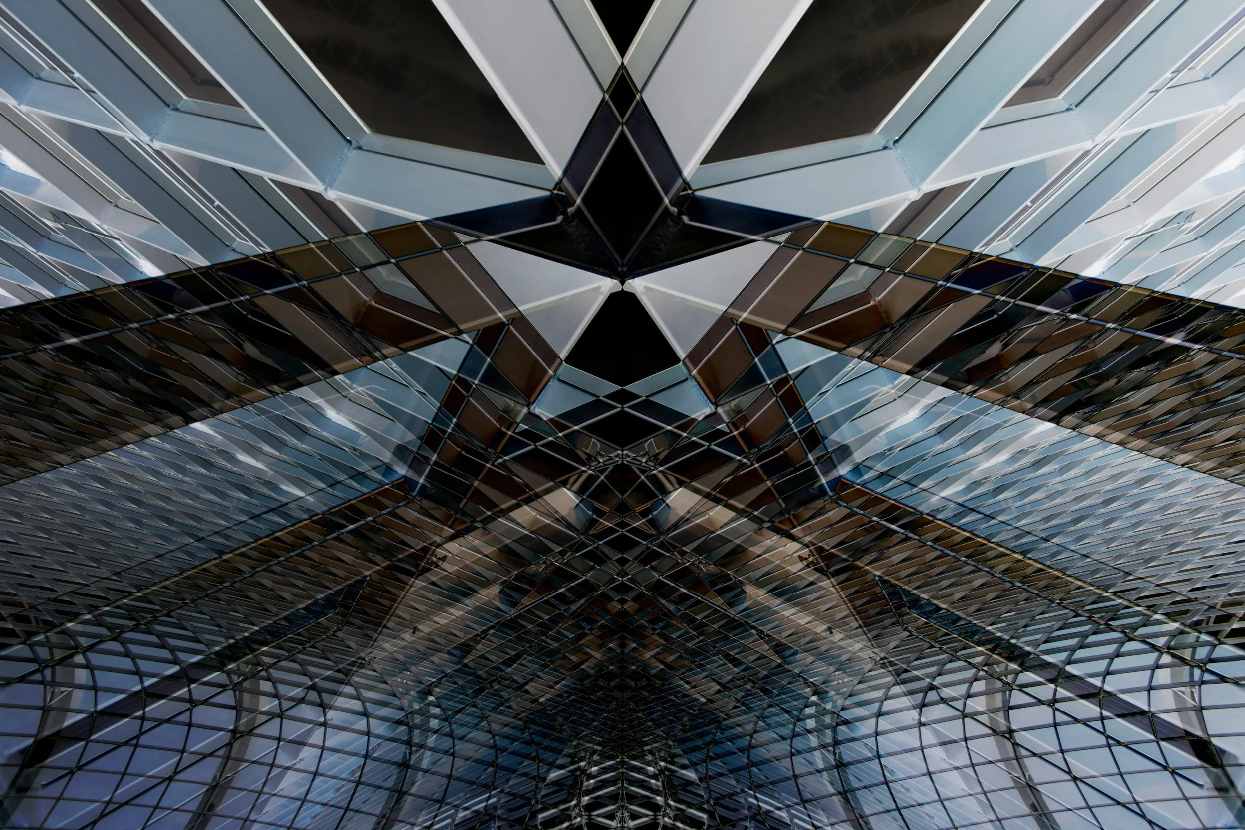 A low-angle view of a modern glass building with an intricate geometric design, reflecting the sky and surrounding structures.