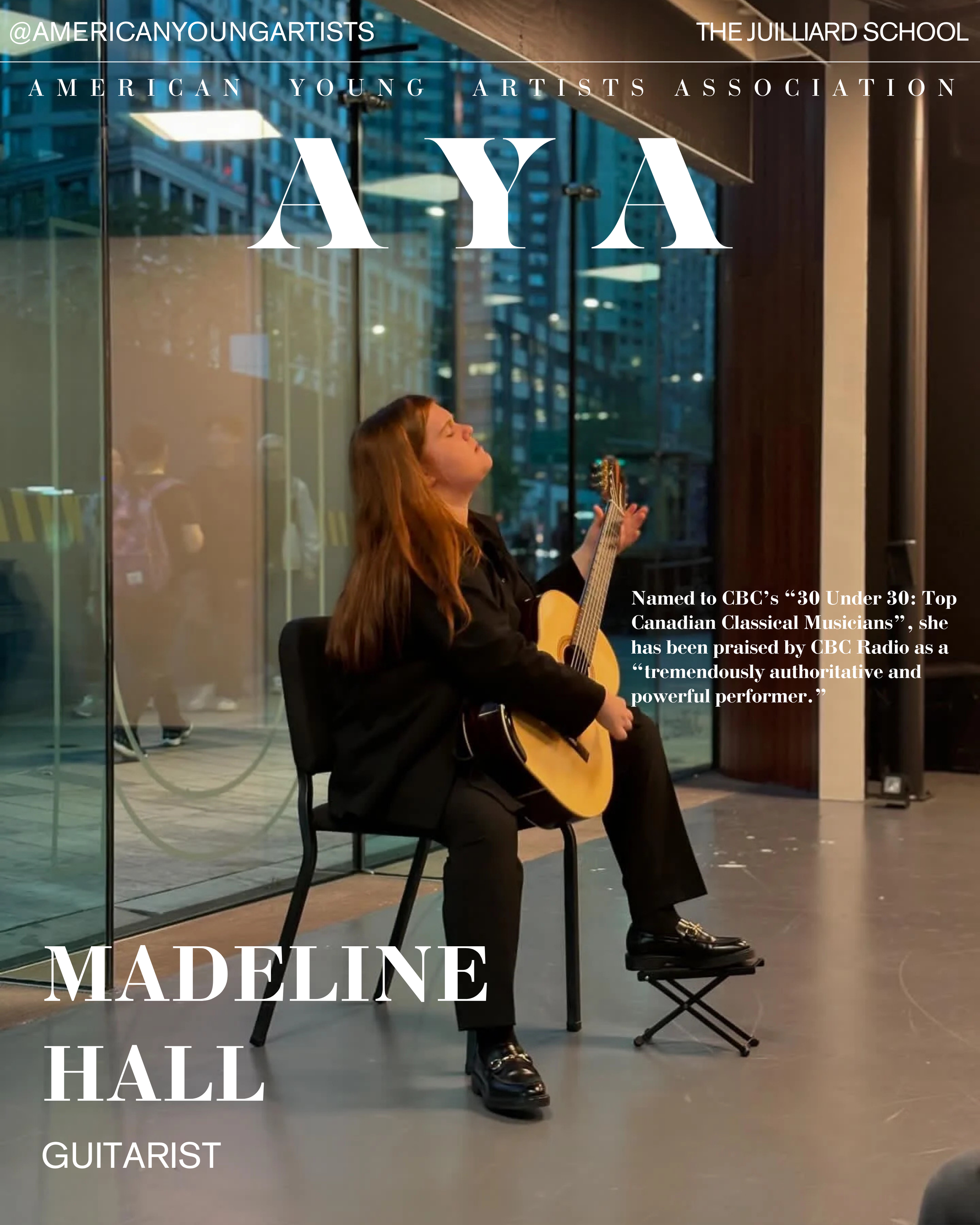 A woman with long brown hair, dressed in black, sitting on a black chair and playing an acoustic guitar, with her eyes closed and head tilted back, in a modern indoor setting with large glass windows and city buildings reflected in the background.