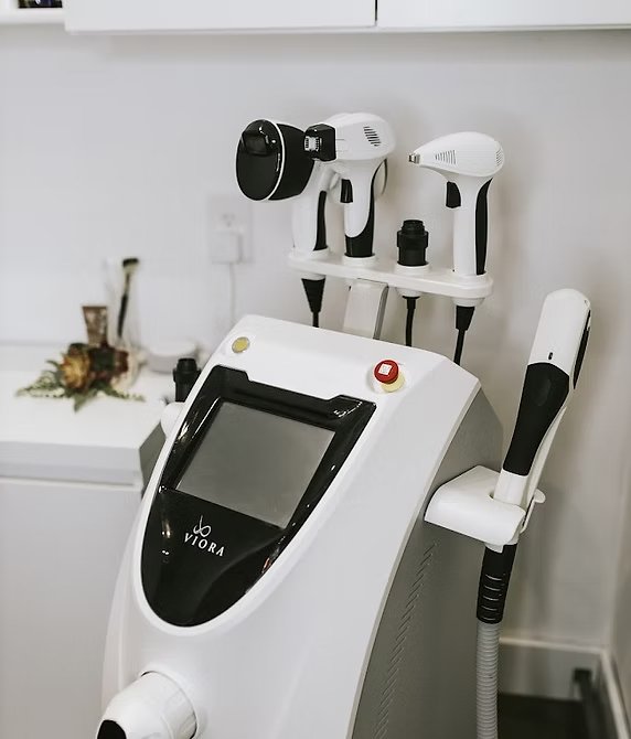 Medical aesthetic device with multiple handpieces attached, located in a clinical setting.