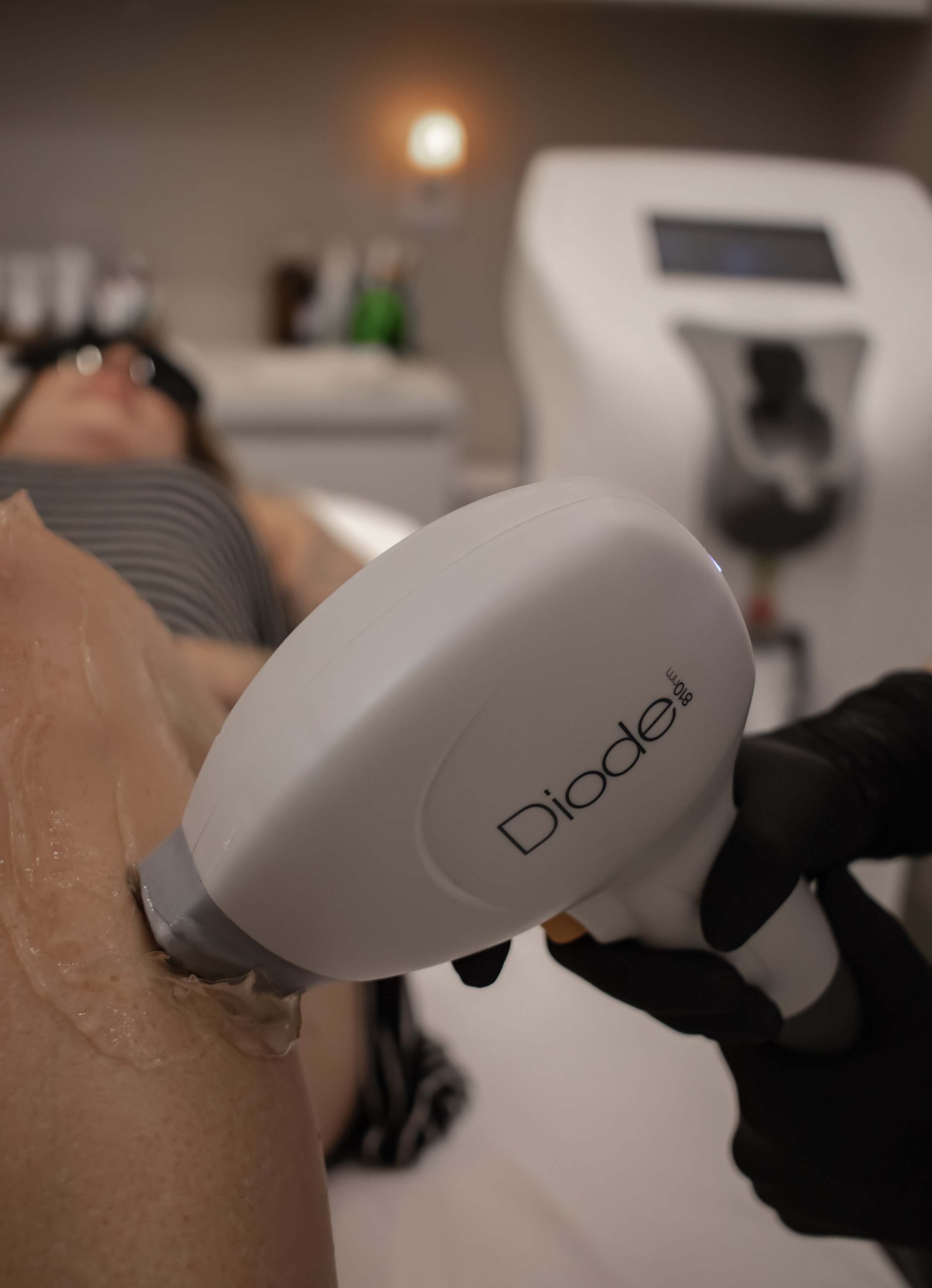 A person receiving a facial treatment with a device labeled 'Diode 890nm' in a spa or clinic setting.