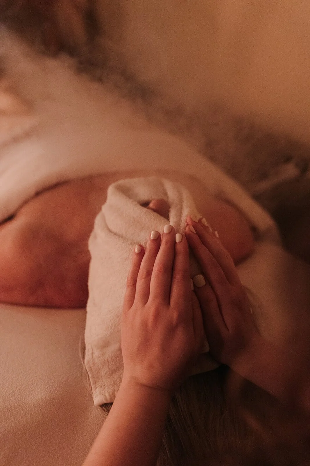 Person lying on a massage table with a towel covering their lower body, and a person performing a massage with their hands on the back.