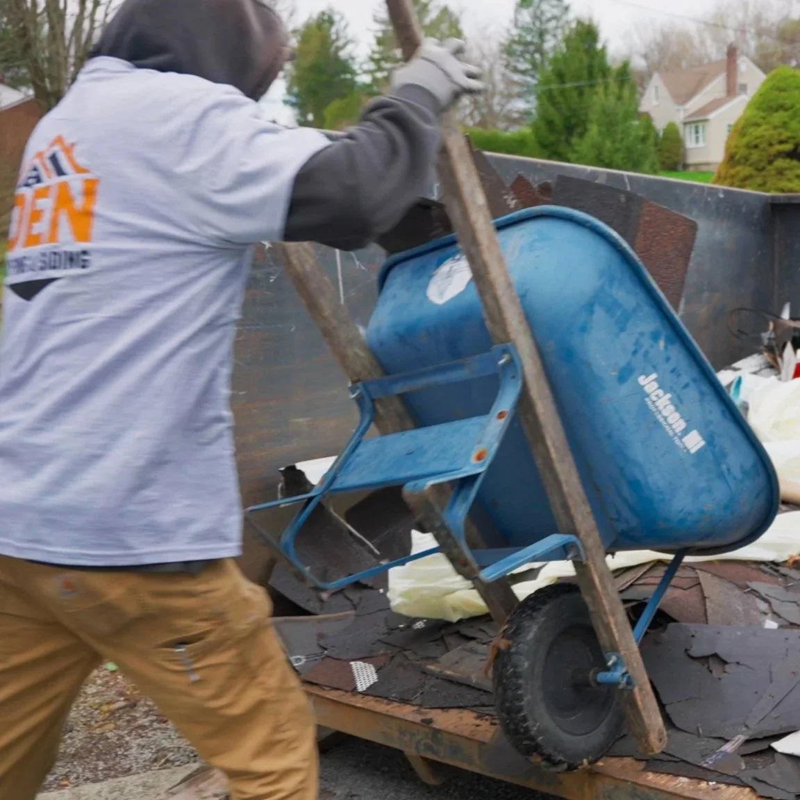 Pittsburgh roofers working outdoors, one with a white hoodie with a business logo and the other with a red hoodie, working on a roof repair project.