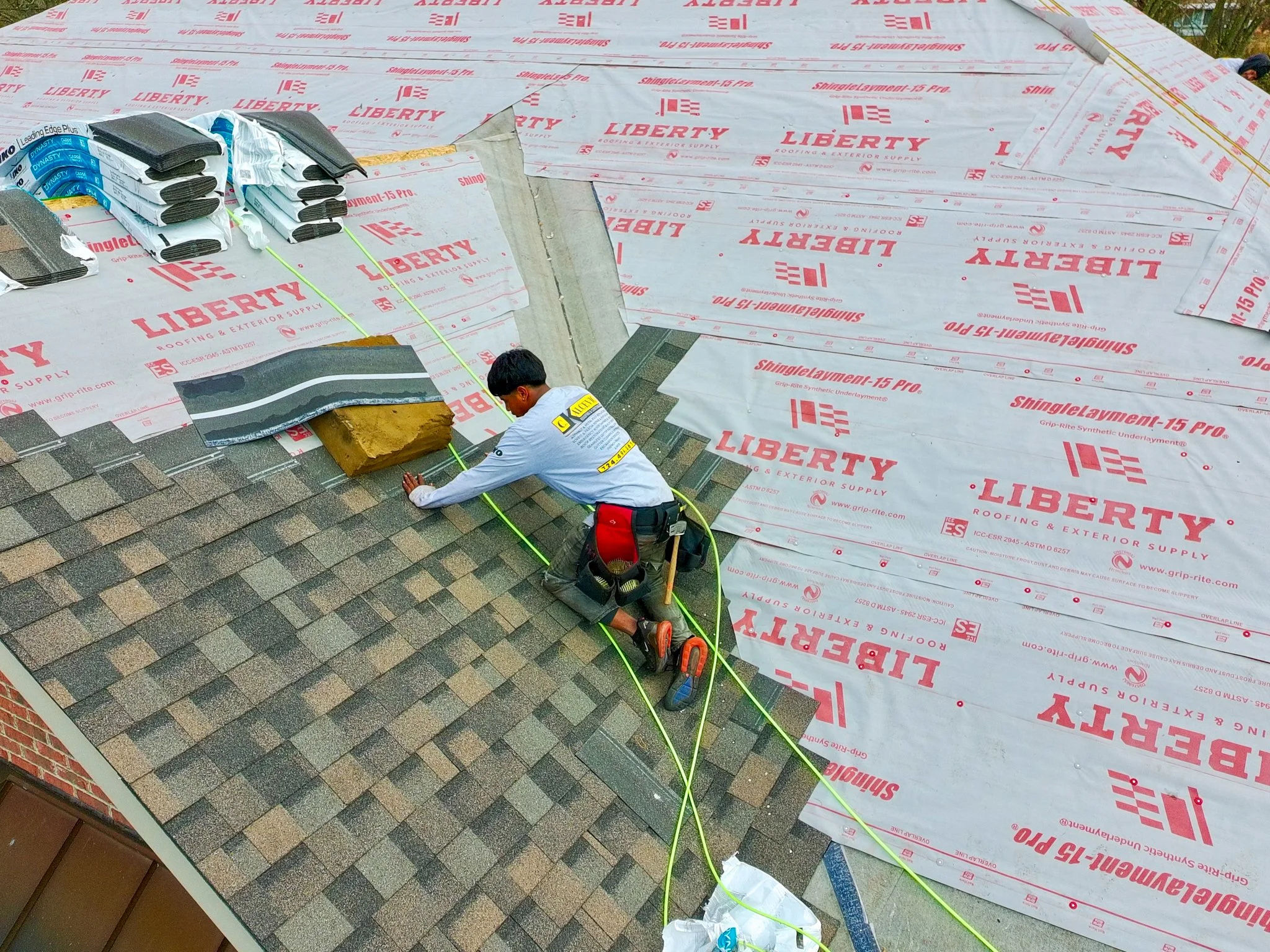 Pittsburgh roofer installing shingles on a house roof with insulation and roofing materials visible.