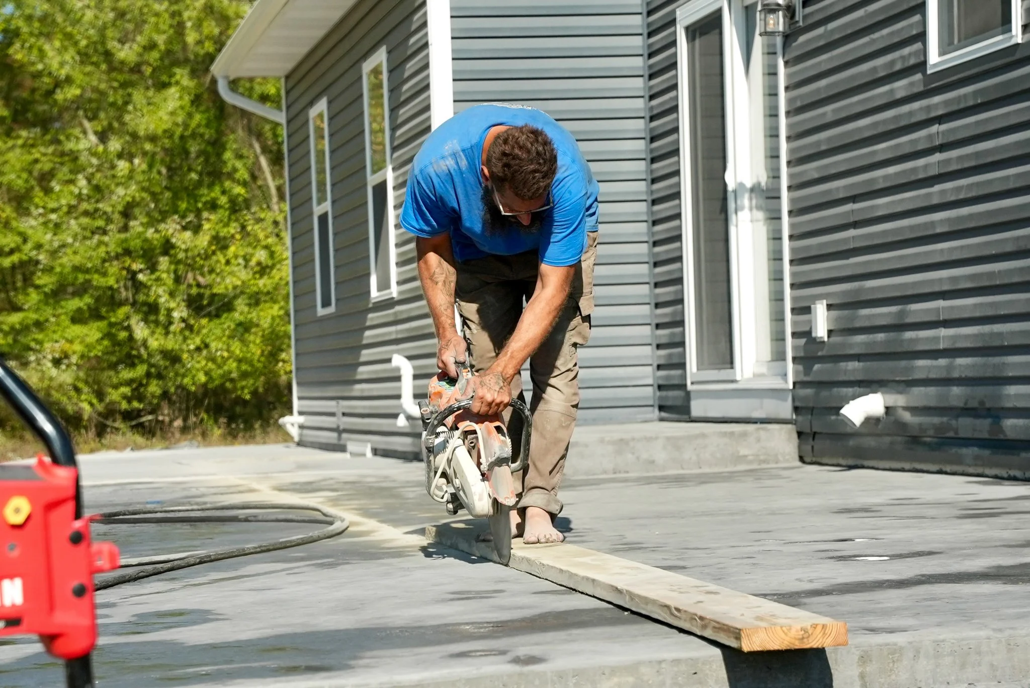 Pittsburgh contractor cutting wood with a circular saw outside a house.