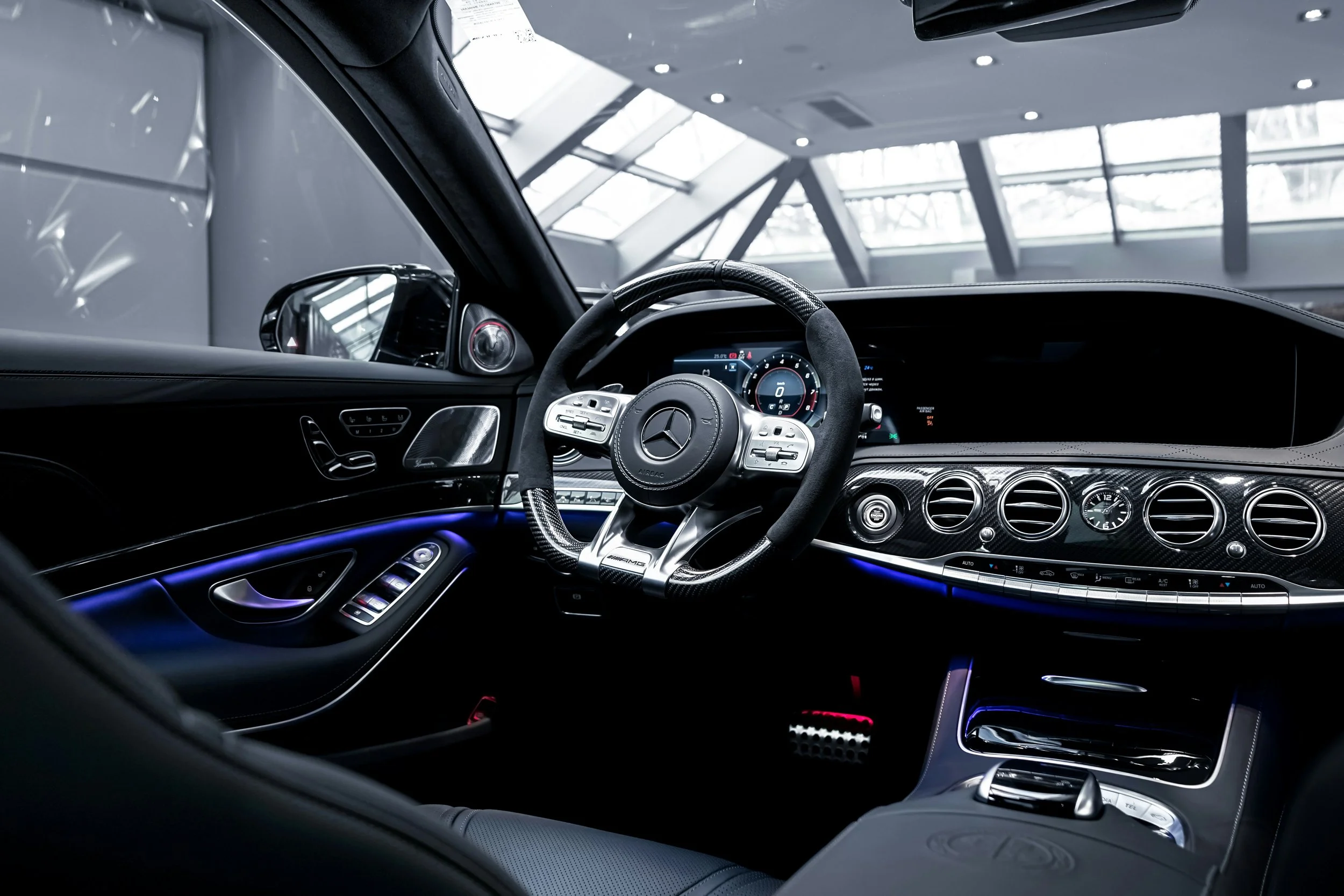 Interior of a luxury car, showing the dashboard, steering wheel, and center console with control buttons and displays.