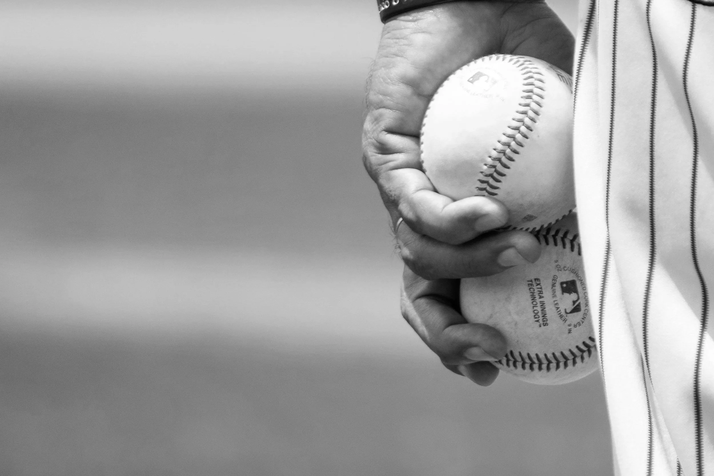 A person holding a baseball in their hand, wearing a striped sports jersey.
