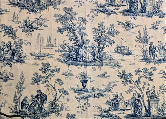 Blue and white toile fabric with pastoral scenes, including people by trees, a boat, and classical figures.