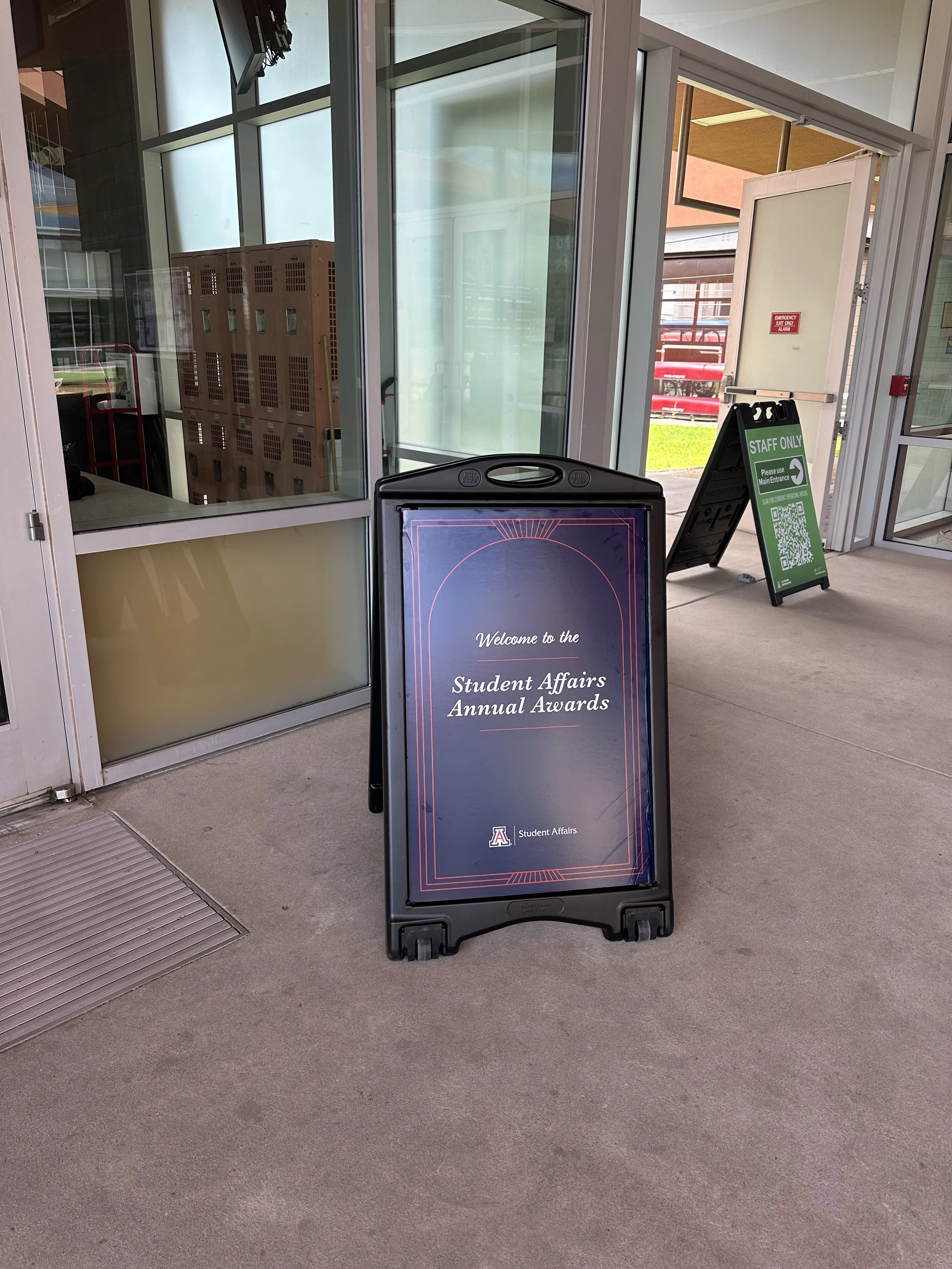 Signboard for the Student Affairs Annual Awards with the University of Arizona logo, placed on a stand outside a building entrance.