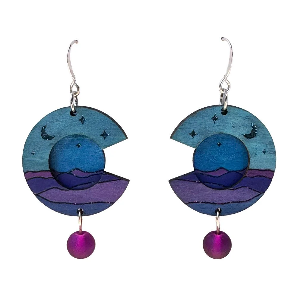 Pair of earrings with circular blue and purple sunset or moonrise designs, featuring a small purple bead dangling at the bottom.