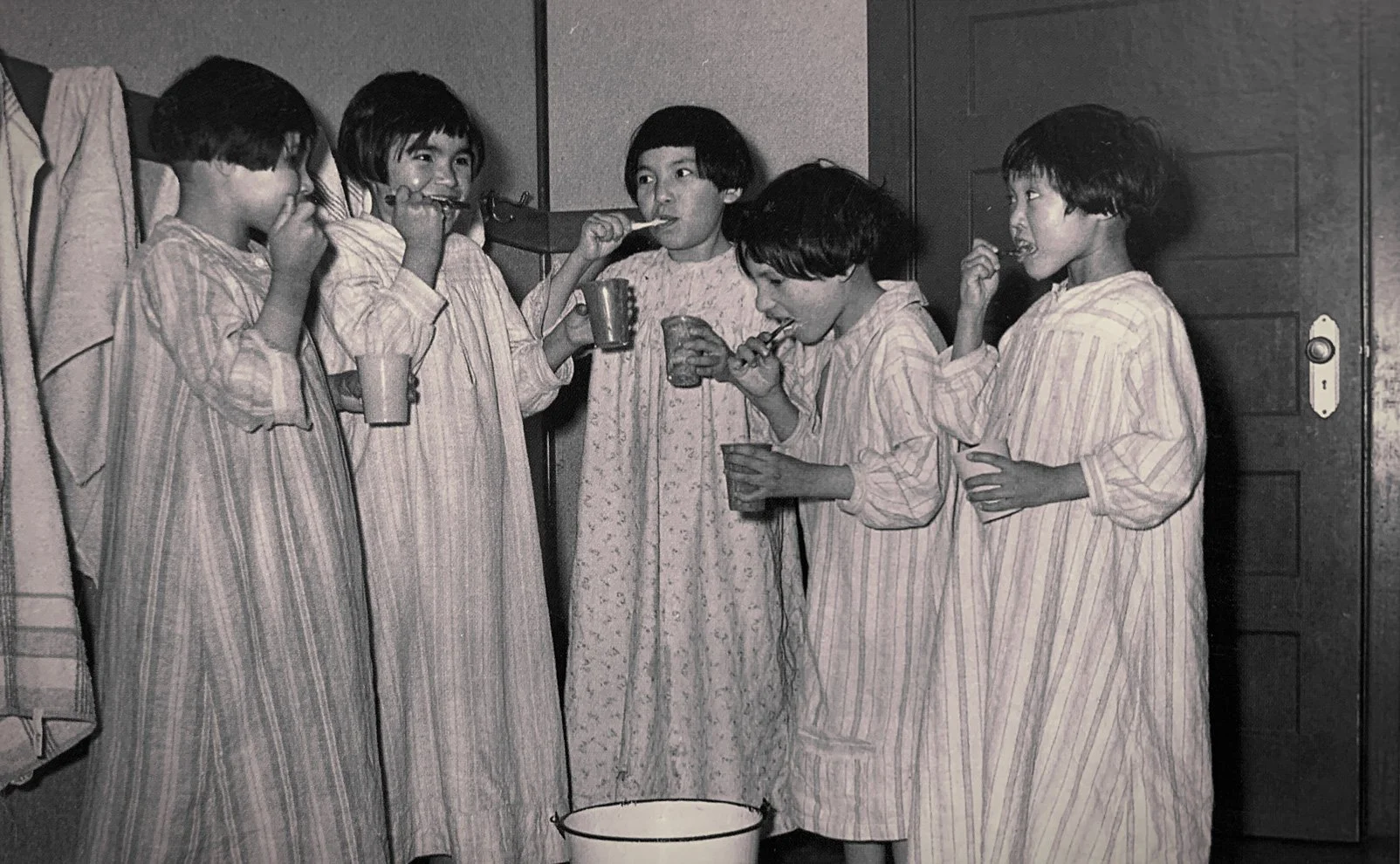 Girls brush their teeth and spit into a bucket at St. Phillip's Indian Residential School. The Anglican school was in Fort George on James Bay in northern Quebec. It opened in February 1933 and closed in 1979.