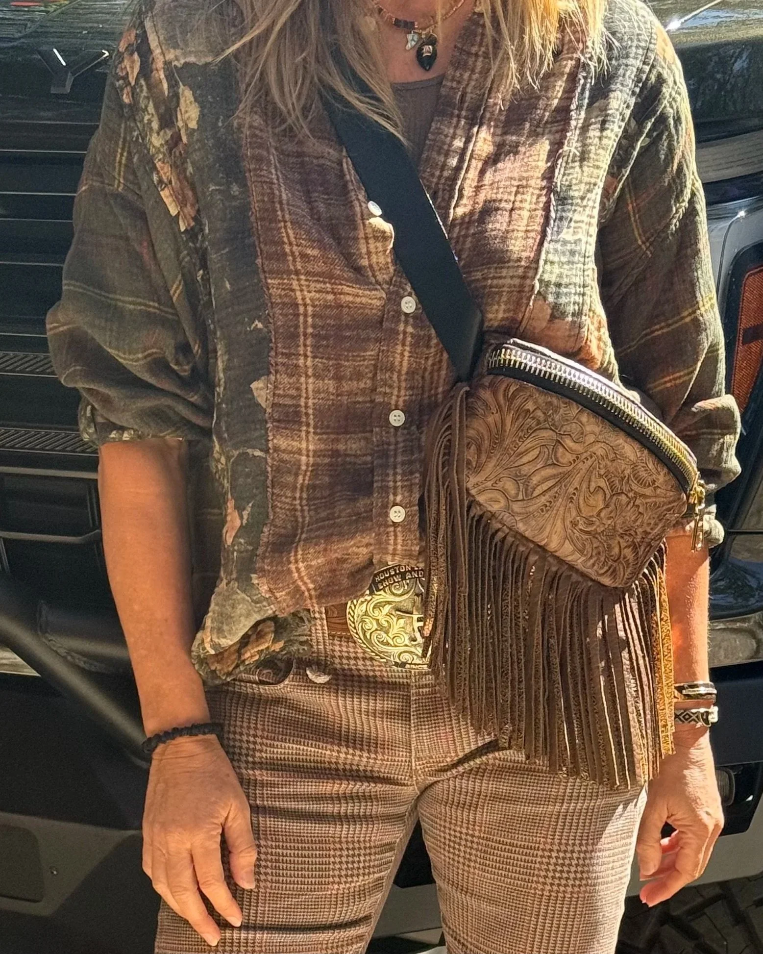 Western-inspired leather crossbody bag featuring an embossed pattern and fringe details.
