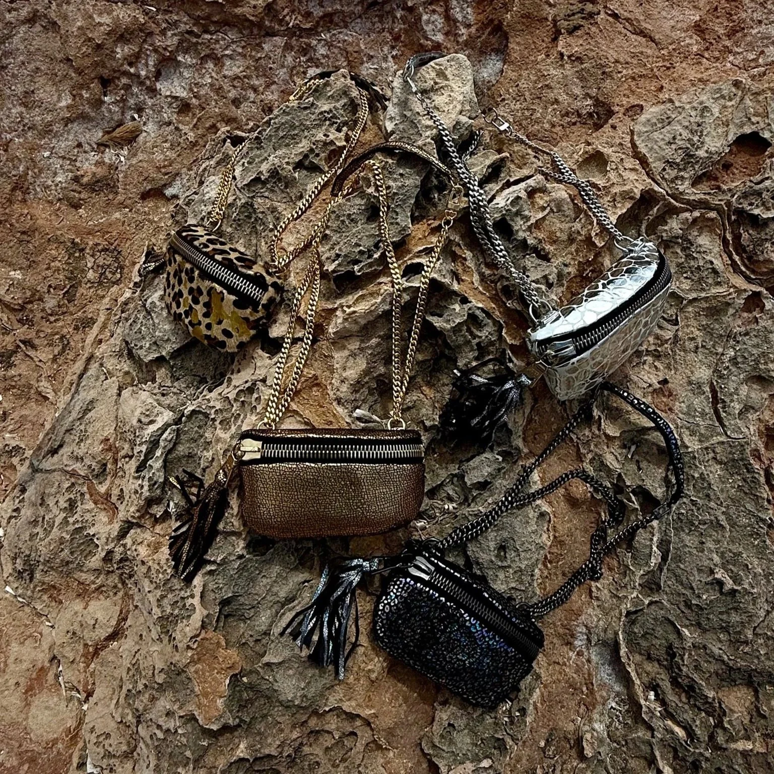 Collection of metallic leather handbags featuring chain straps, textured finishes, and statement designs.