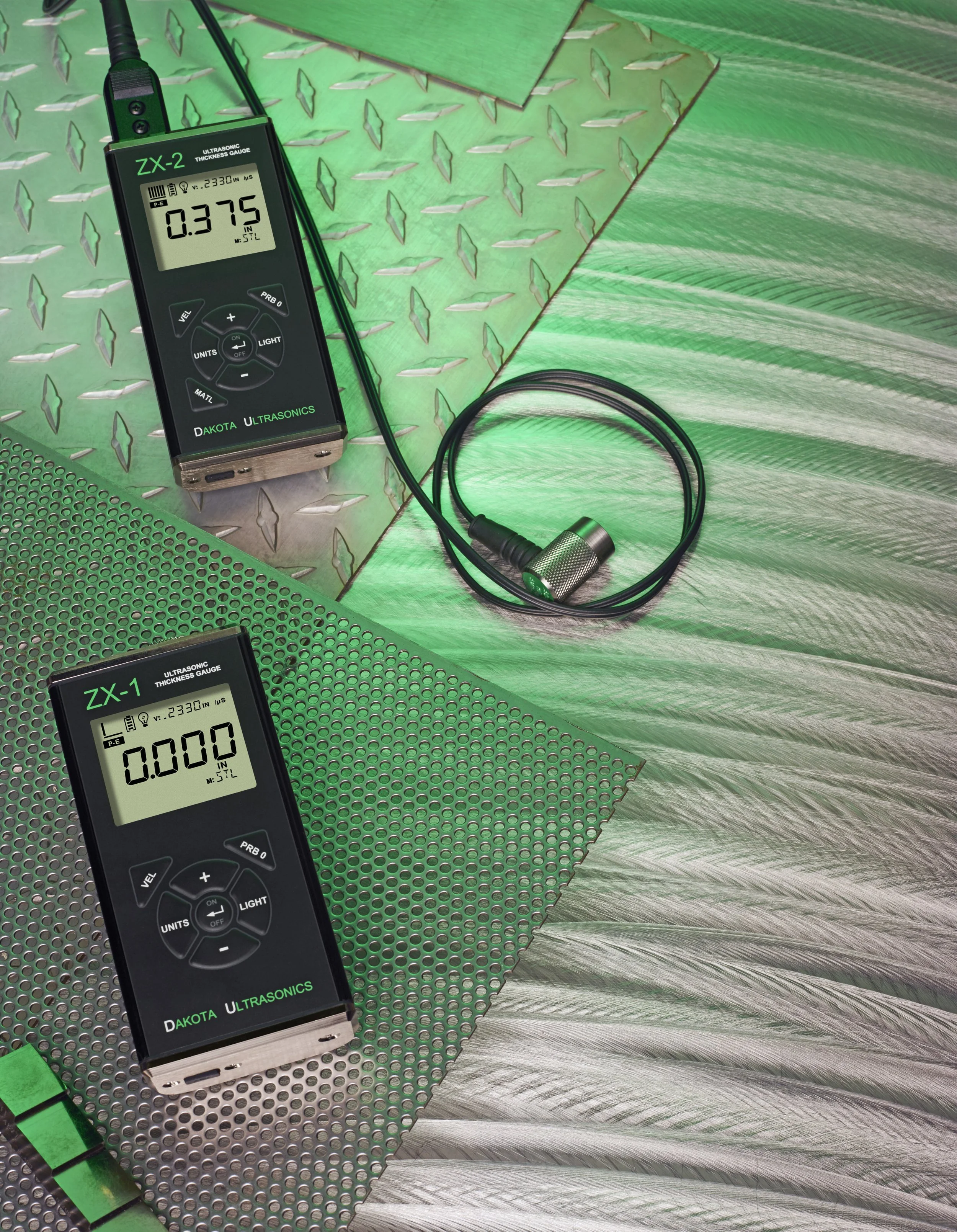 Dos medidores de espesor ultrasónico sobre superficies metálicas, uno mostrando 0.375 pulgadas y otro 0.000 pulgadas, con una reflectante de metal en el fondo.